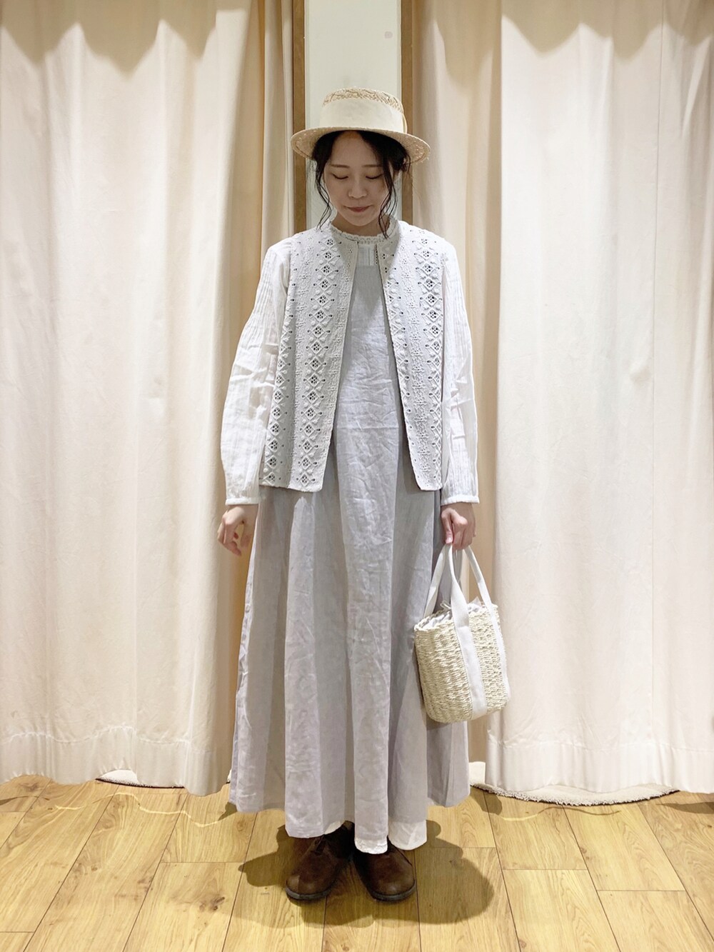 グレー系のワンピース、ホワイト系のベスト、ホワイト系のスカートを着用したレディースの春コーディネートの2枚目の写真