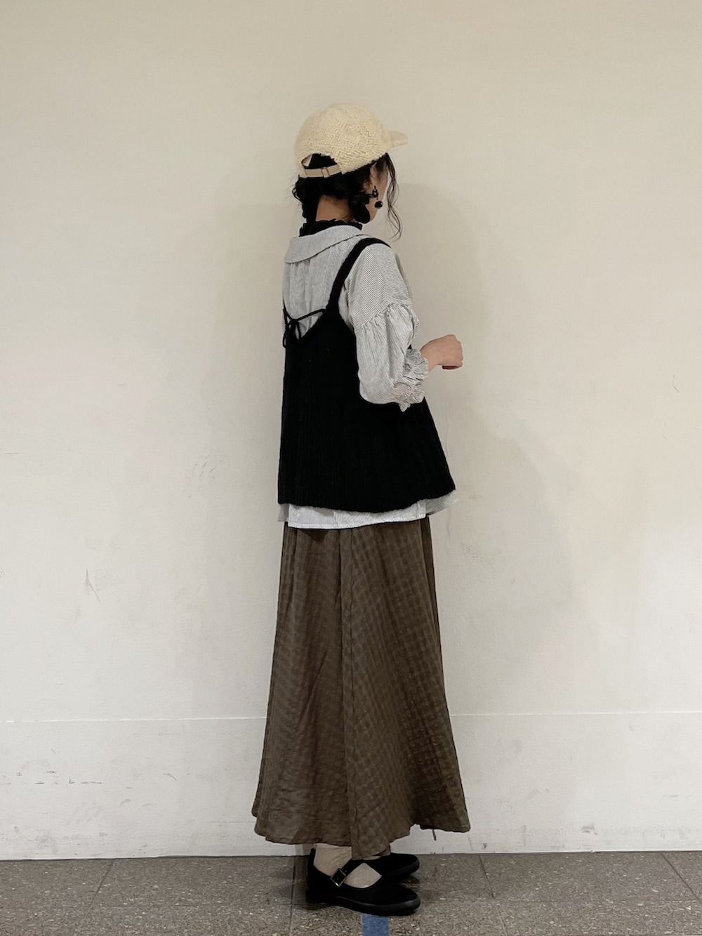 ブラック系のニット/セーター、グレー系のシャツ/ブラウス、ブラック系のタンクトップを着用したレディースの秋コーディネートの3枚目の写真