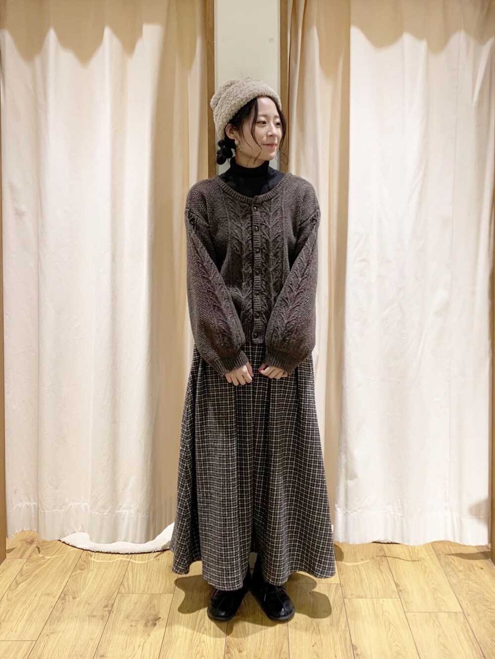 グレー系のニット/セーター、ブラウン系のカーディガン/ボレロ、ブラウン系のスカートを着用したレディースの冬コーディネートの2枚目の写真