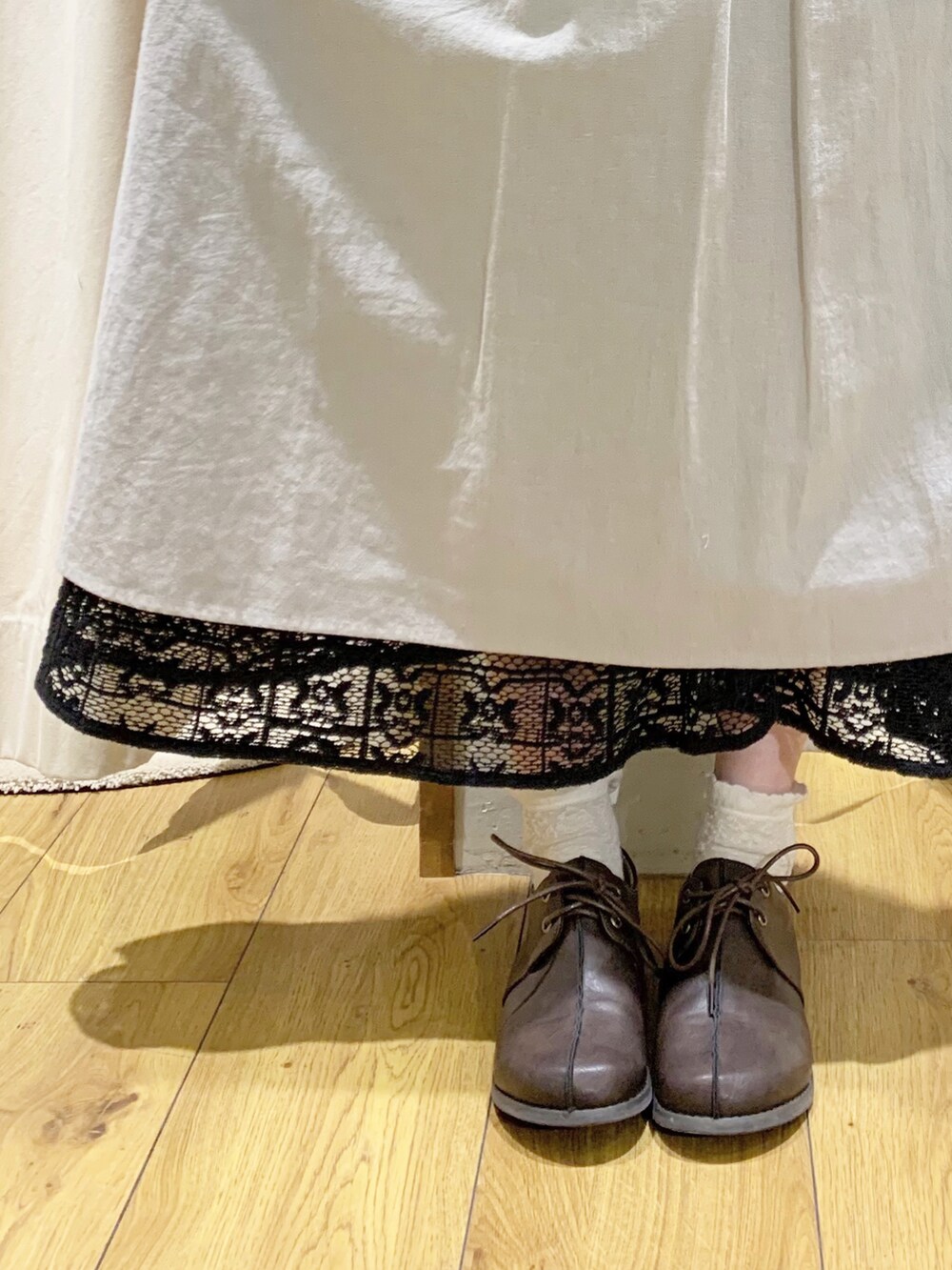 グレー系のベスト、グレー系のワンピース、ブラック系のスカートを着用したレディースの春コーディネートの4枚目の写真