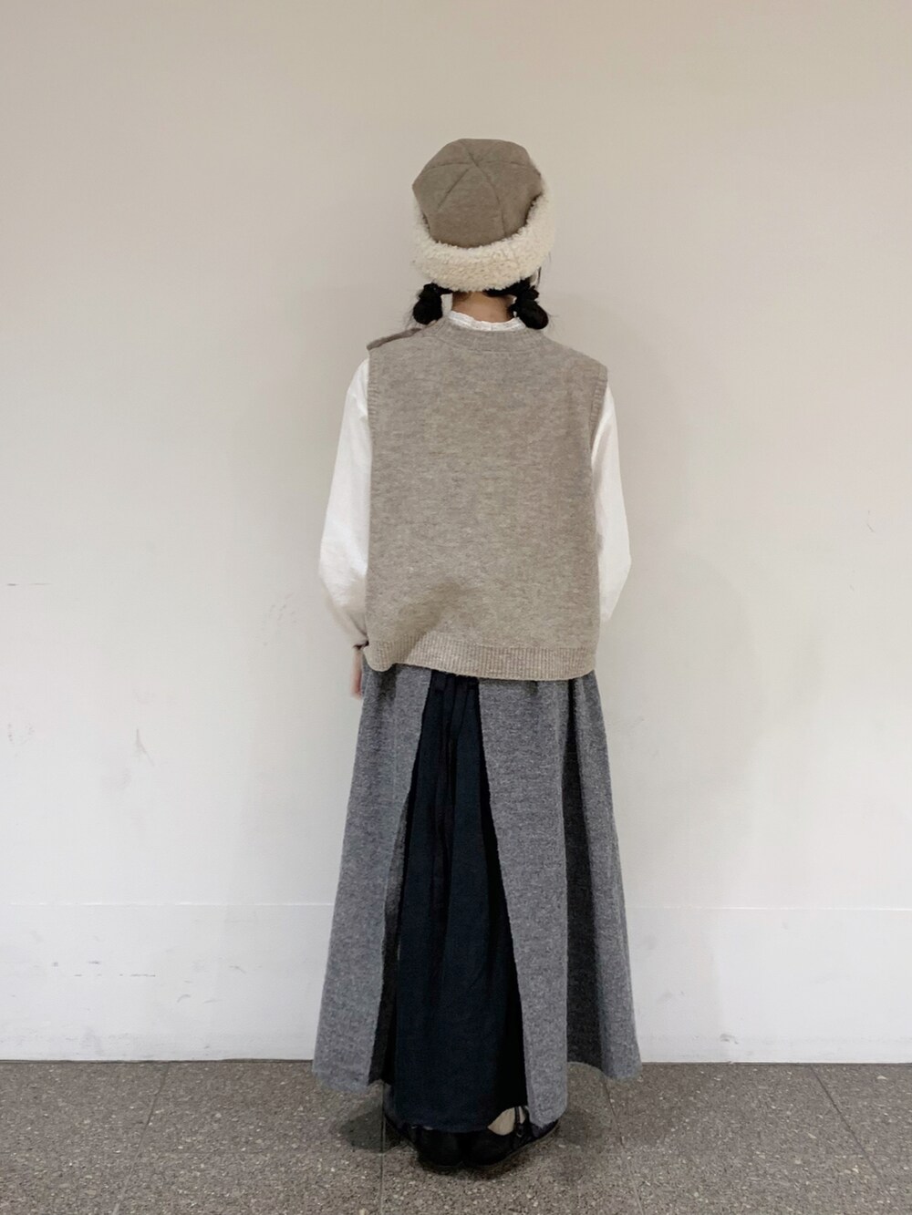 ベージュ系のベスト、ホワイト系のシャツ/ブラウス、ブラック系のスカートを着用したレディースの秋コーディネートの3枚目の写真