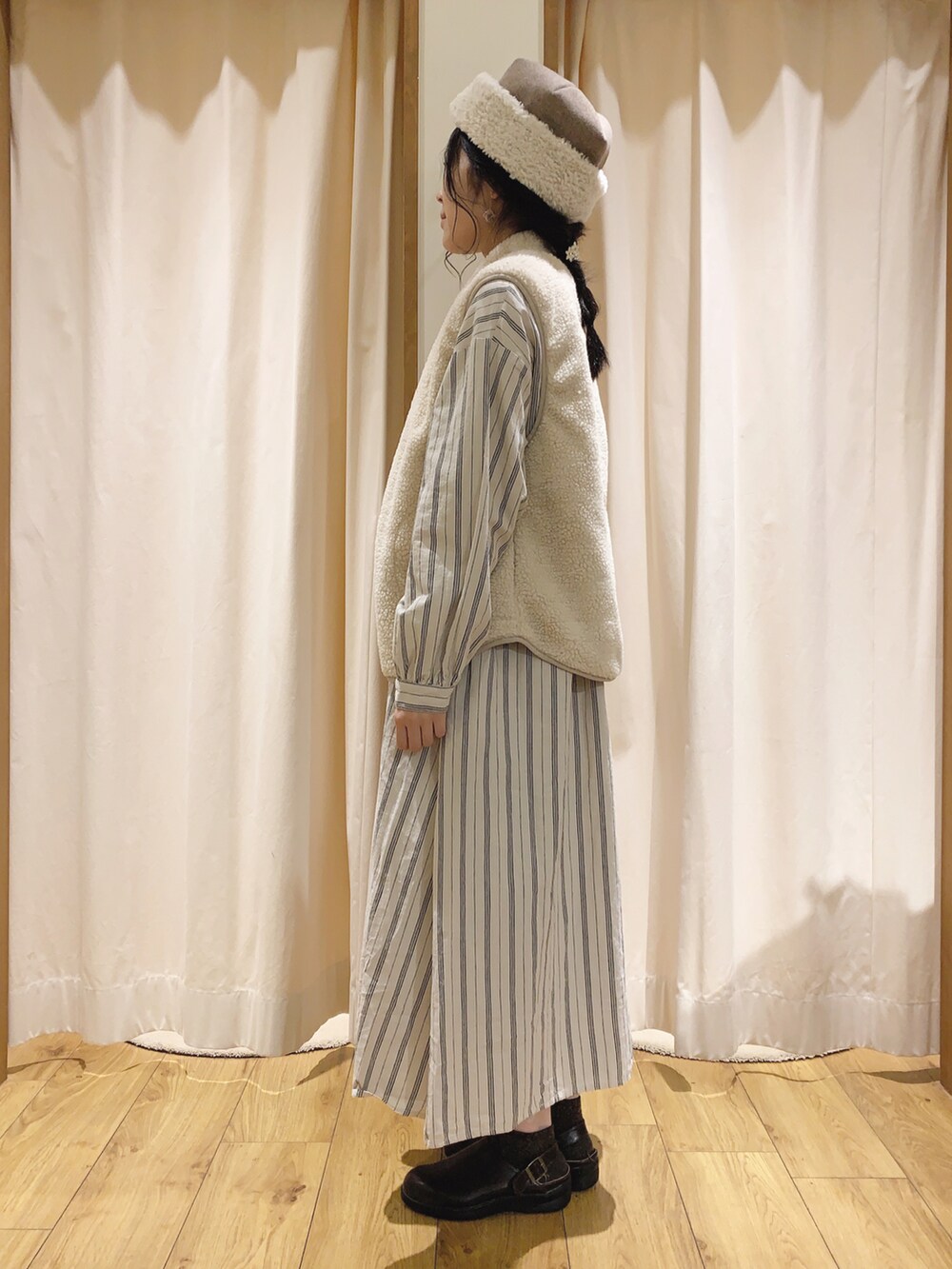 ホワイト系のベスト、ホワイト系のワンピース、ベージュ系のスカートを着用したレディースの秋コーディネートの3枚目の写真