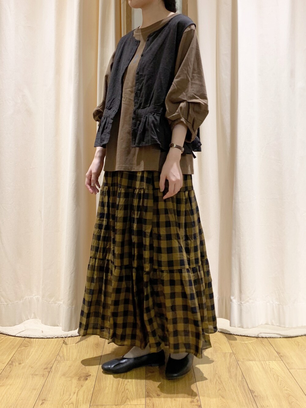 ブラウン系のTシャツ/カットソー、グレー系のベスト、イエロー系のスカートを着用したレディースの夏コーディネートの2枚目の写真