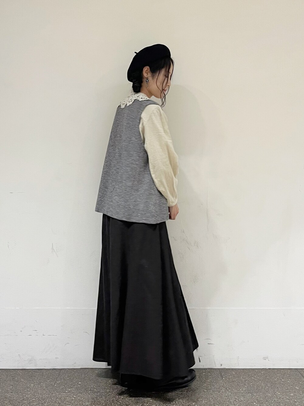 グレー系のベスト、ベージュ系のシャツ/ブラウス、グレー系のスカートを着用したレディースの秋コーディネートの2枚目の写真