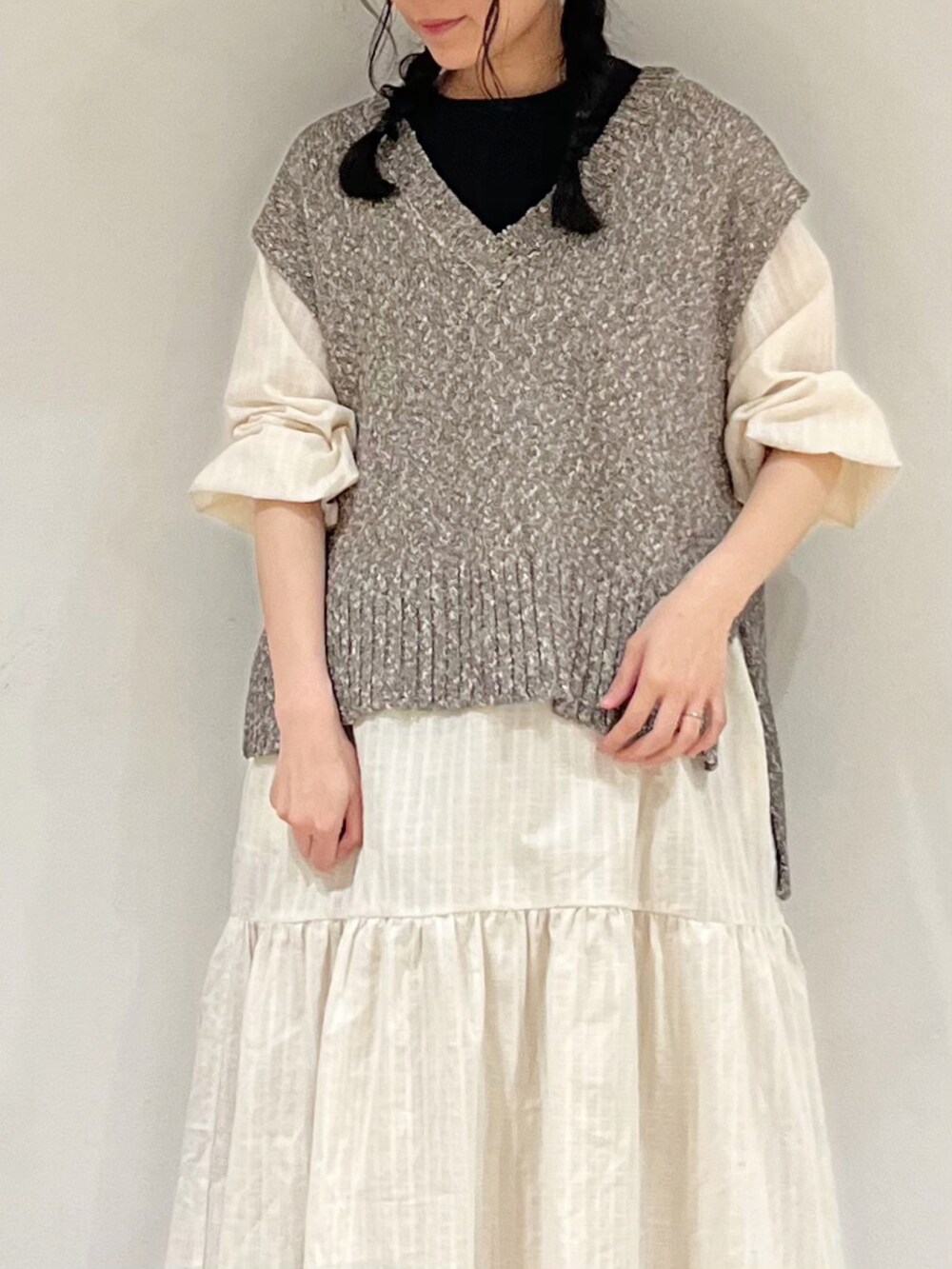 ブラウン系のベスト、ホワイト系のワンピース、ベージュ系のスカートを着用したレディースの冬コーディネートの5枚目の写真