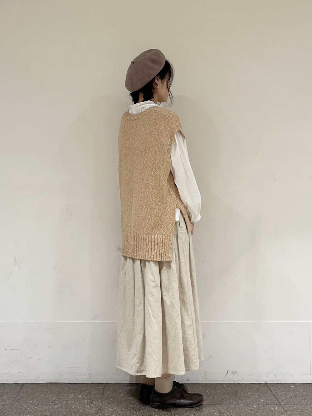ベージュ系のベスト、ベージュ系のスカート、ホワイト系のハンドバッグを着用したレディースの冬コーディネートの3枚目の写真