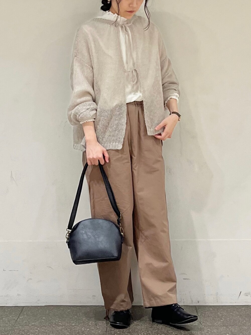 ブラウン系のその他パンツ、ブラック系のハンドバッグ、グレー系のカーディガン/ボレロを着用したレディースの冬コーディネートの2枚目の写真