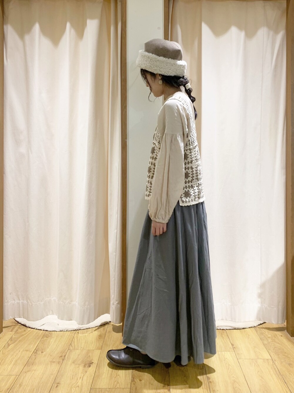 ホワイト系のベスト、ホワイト系のシャツ/ブラウス、グリーン系のスカートを着用したレディースの秋コーディネートの2枚目の写真