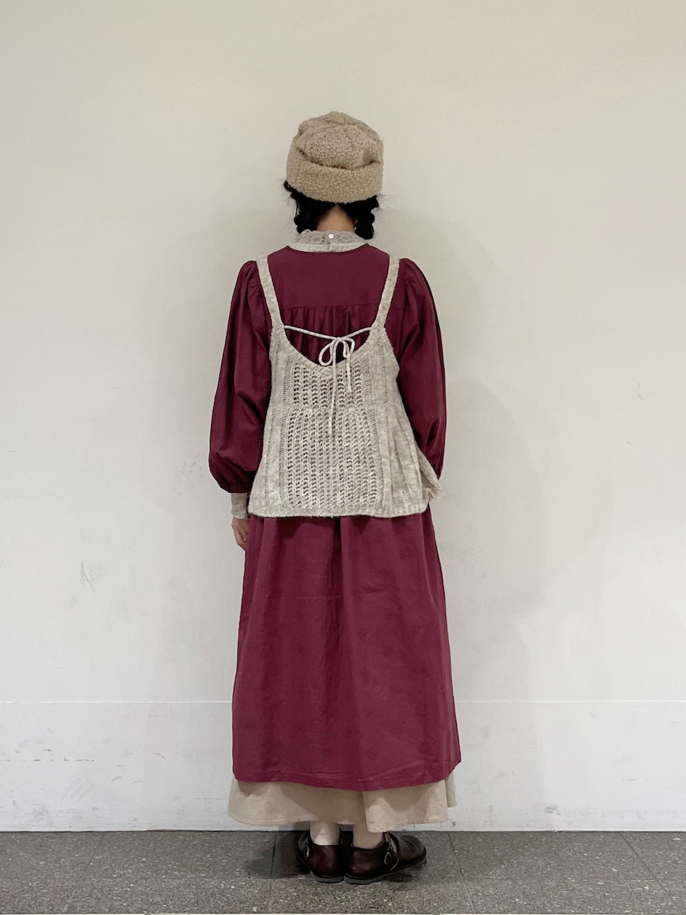 レッド系のワンピース、ホワイト系のニット/セーター、ベージュ系のスカートを着用したレディースの秋コーディネートの3枚目の写真