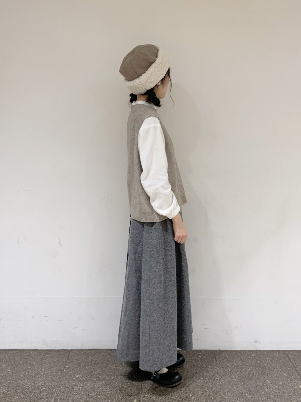 ベージュ系のベスト、ホワイト系のシャツ/ブラウス、ブラック系のスカートを着用したレディースの秋コーディネートの2枚目の写真