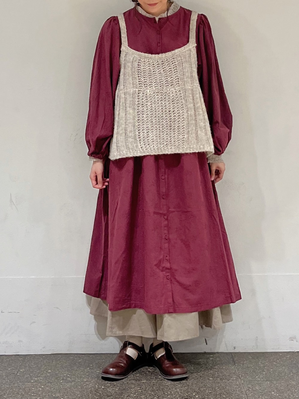 レッド系のワンピース、ホワイト系のニット/セーター、ベージュ系のスカートを着用したレディースの秋コーディネートの4枚目の写真