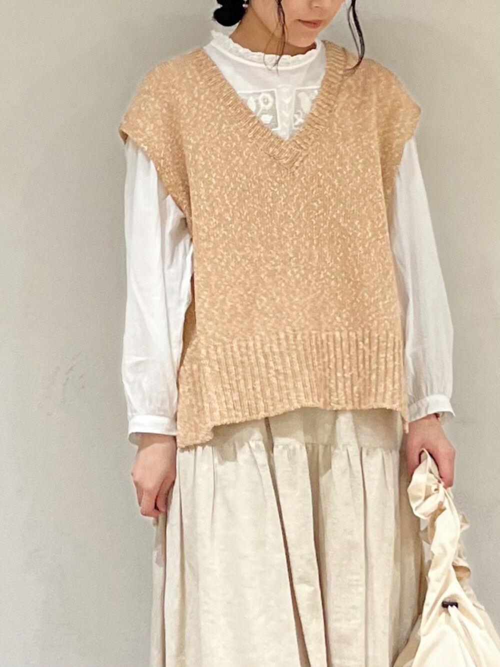 ベージュ系のベスト、ベージュ系のスカート、ホワイト系のハンドバッグを着用したレディースの冬コーディネートの5枚目の写真