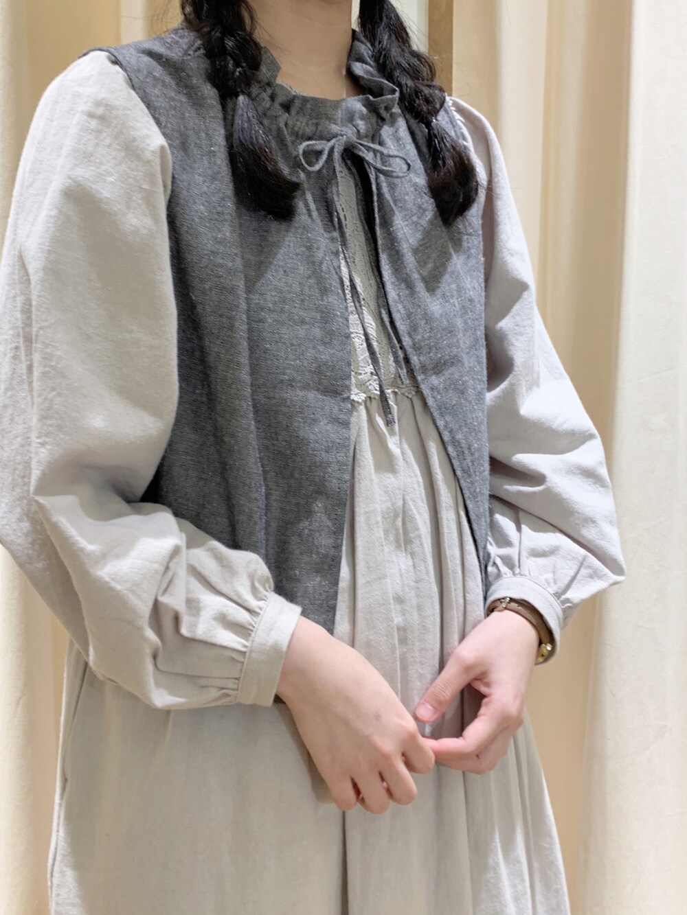 グレー系のベスト、グレー系のワンピース、ブラック系のスカートを着用したレディースの春コーディネートの5枚目の写真