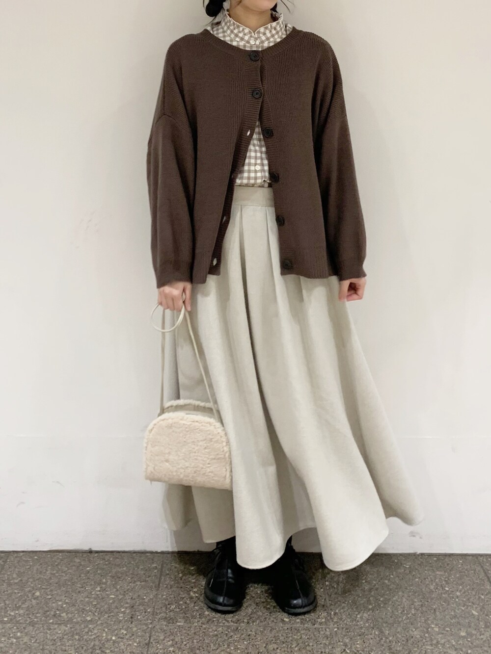 ブラウン系のニット/セーター、ベージュ系のシャツ/ブラウス、ベージュ系のスカートを着用したレディースの冬コーディネートの3枚目の写真