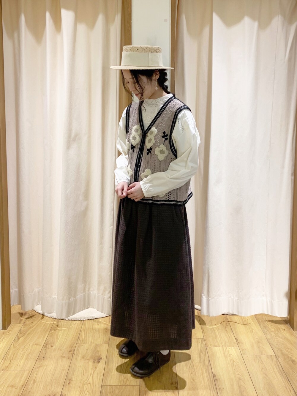 ベージュ系のベスト、ホワイト系のシャツ/ブラウス、グレー系のスカートを着用したレディースの春コーディネートの2枚目の写真