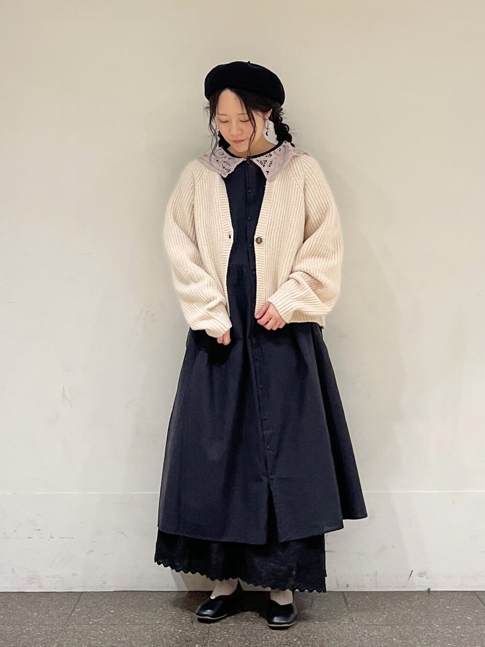 ブラック系のワンピース、ベージュ系のカーディガン/ボレロ、ブラック系のスカートを着用したレディースの春コーディネートの2枚目の写真
