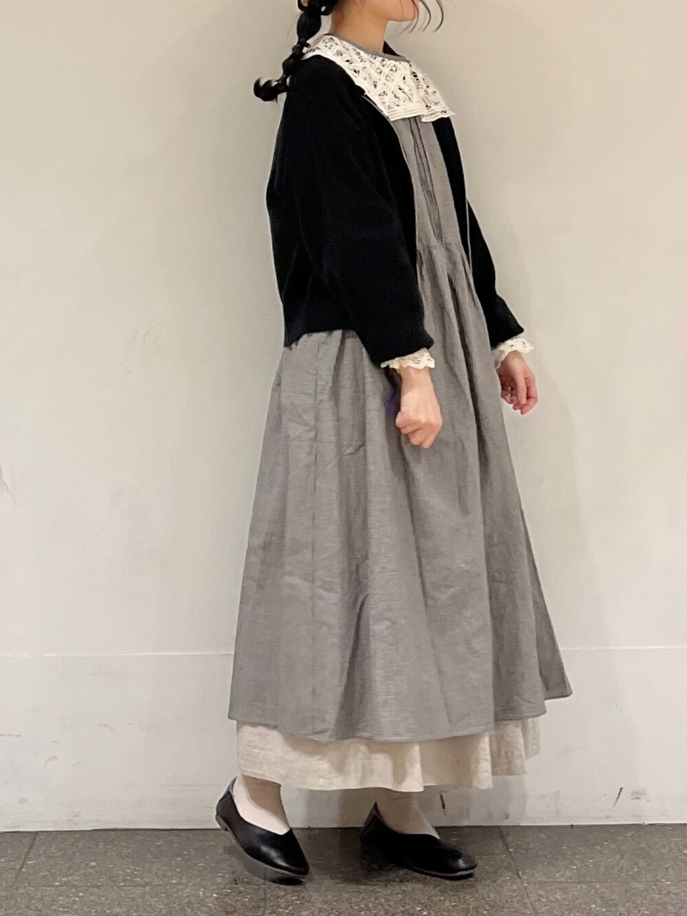 グレー系のワンピース、ブラック系のカーディガン/ボレロ、グレー系のスカートを着用したレディースの春コーディネートの2枚目の写真