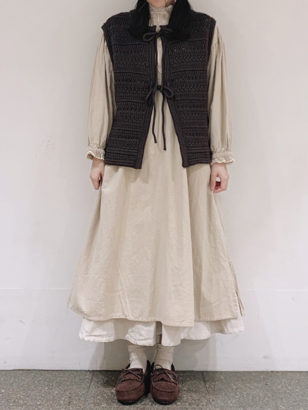 ブラウン系のベスト、ホワイト系のワンピース、ベージュ系のTシャツ/カットソーを着用したレディースの冬コーディネートの2枚目の写真