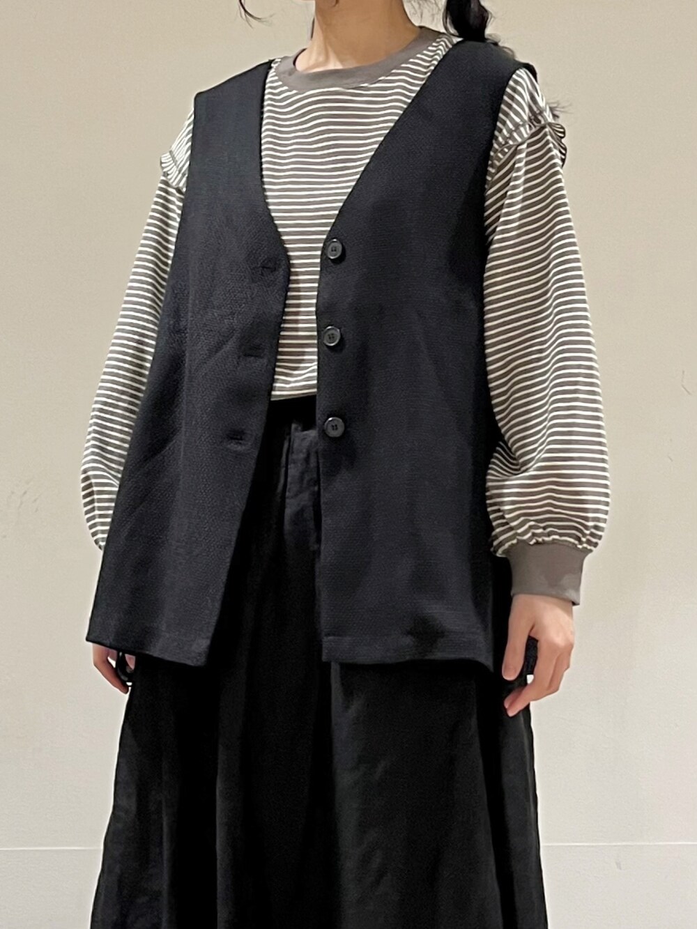 ブラウン系のTシャツ/カットソー、グレー系のベスト、ブラック系のスカートを着用したレディースの春コーディネートの5枚目の写真