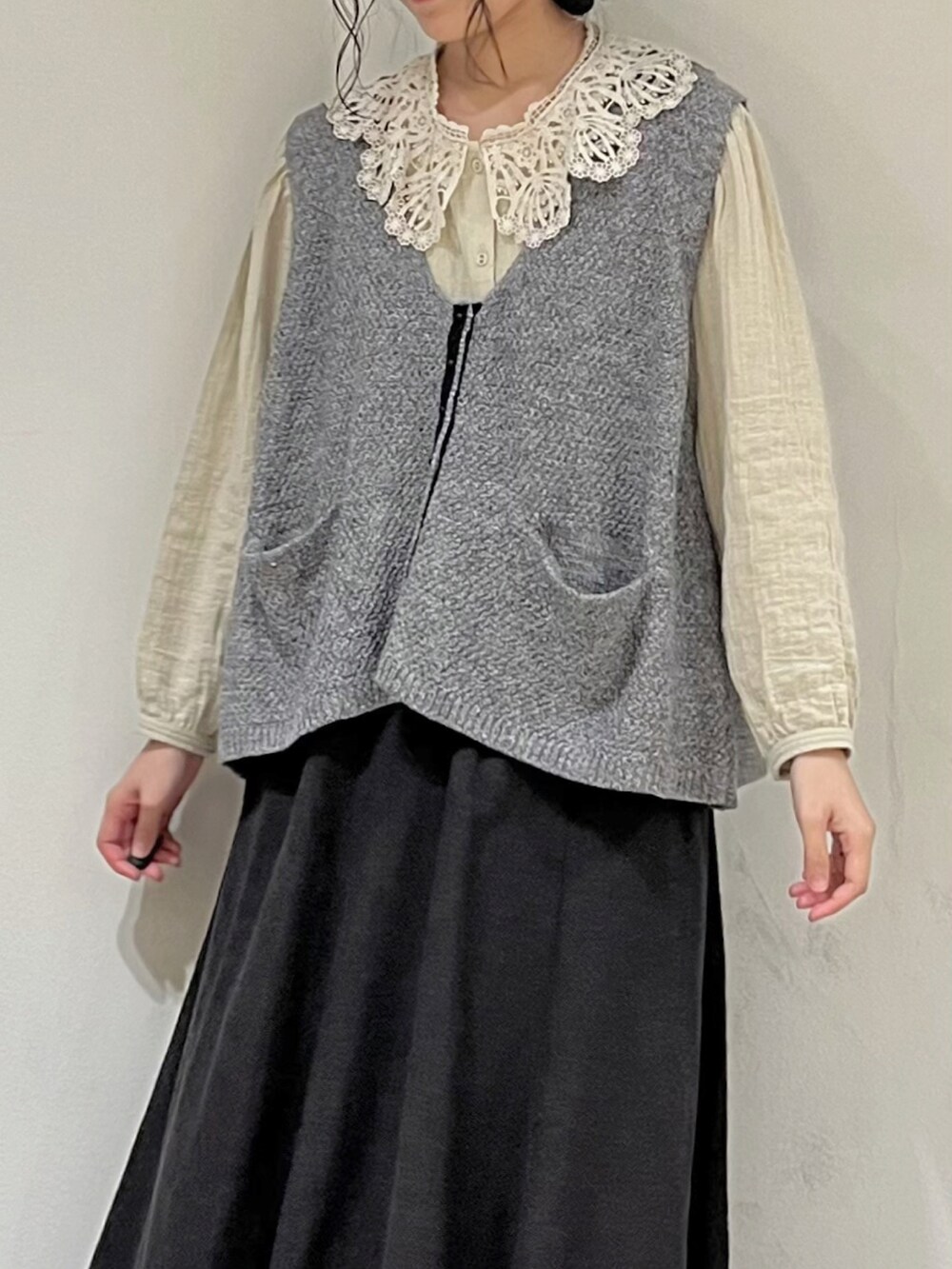 グレー系のベスト、ベージュ系のシャツ/ブラウス、グレー系のスカートを着用したレディースの秋コーディネートの5枚目の写真