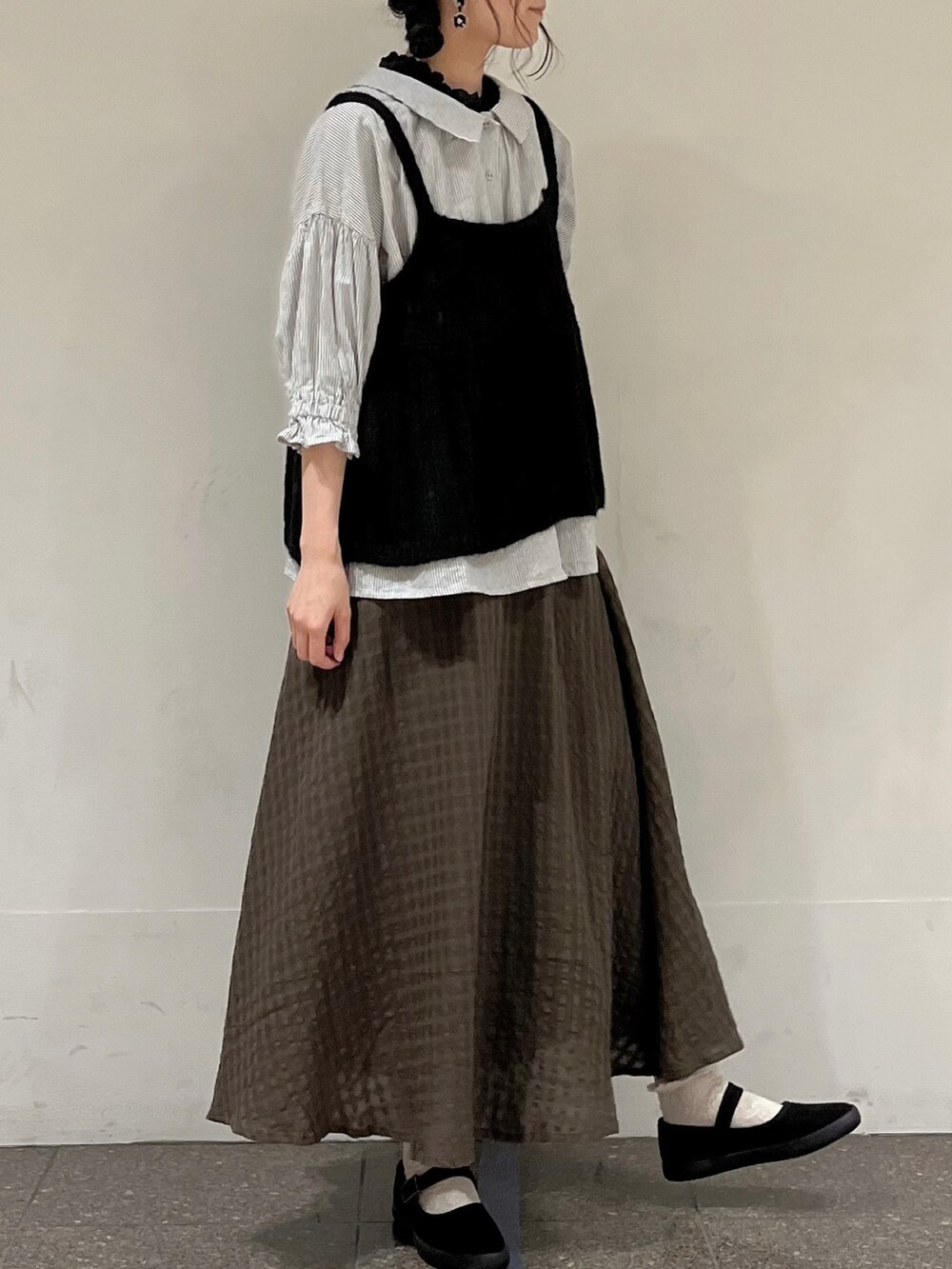 ブラック系のニット/セーター、グレー系のシャツ/ブラウス、ブラック系のタンクトップを着用したレディースの秋コーディネートの2枚目の写真