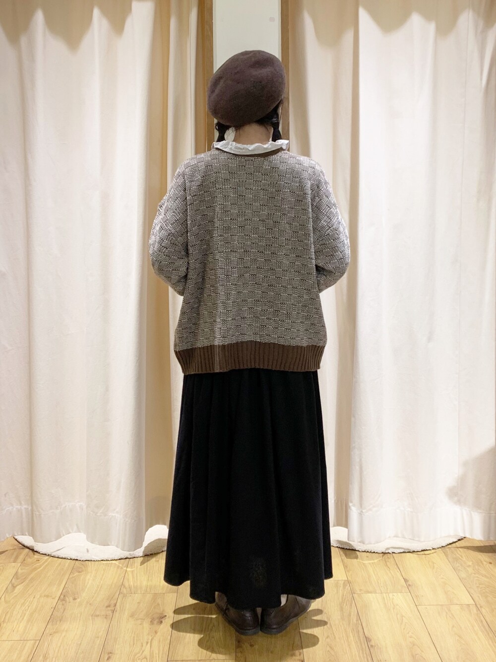 ブラウン系のニット/セーター、ブラック系のスカート、ホワイト系のシャツ/ブラウスを着用したレディースの秋コーディネートの4枚目の写真