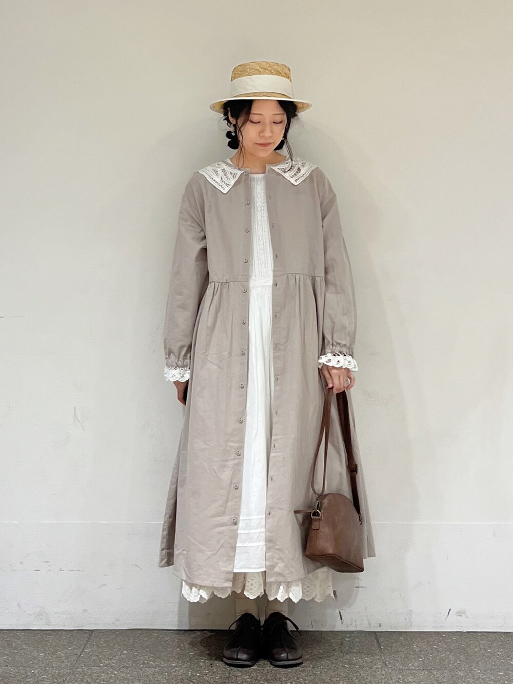 ホワイト系のワンピース、ホワイト系のスカート、ブラウン系のハンドバッグを着用したレディースの冬コーディネートの2枚目の写真