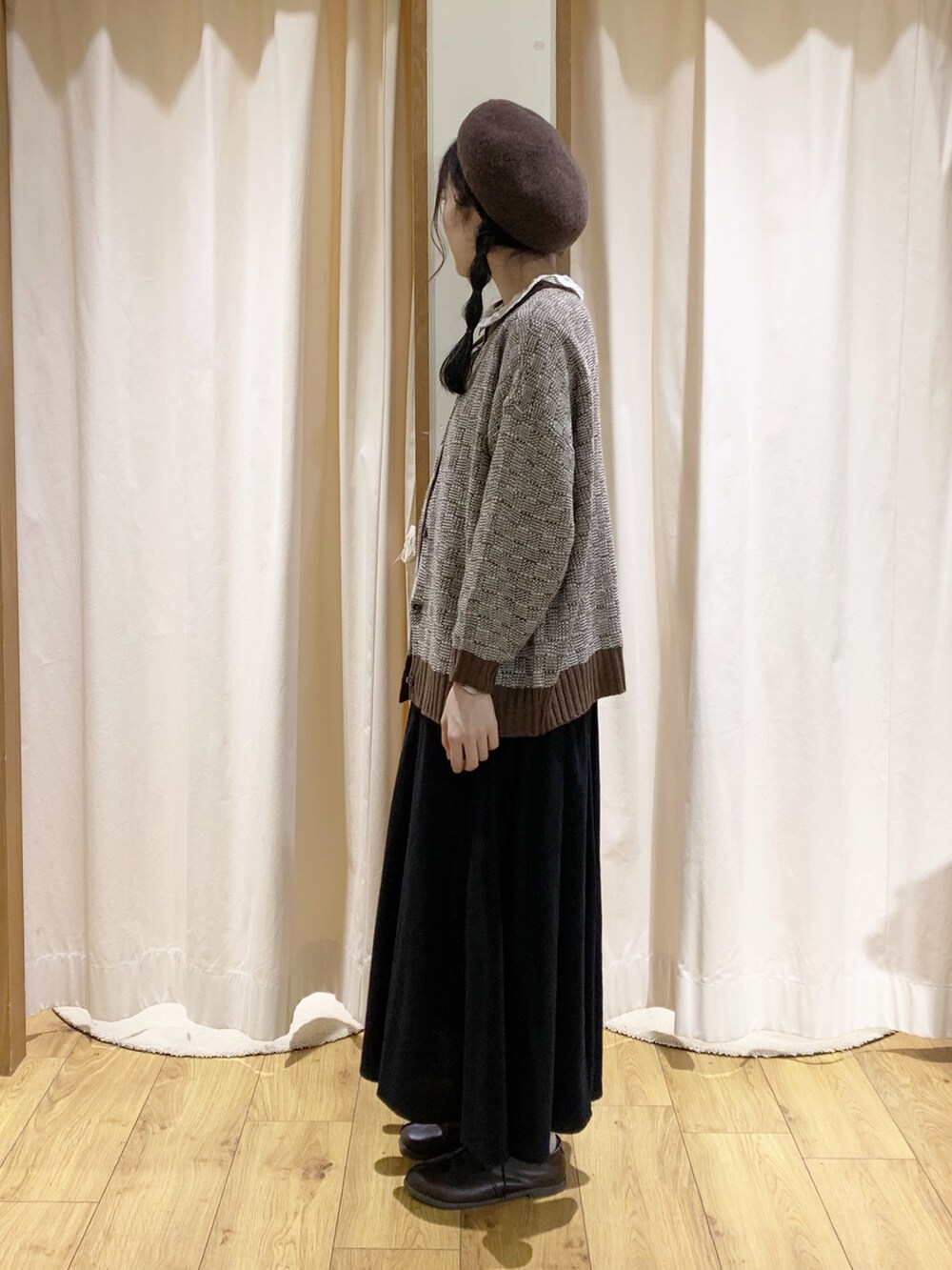 ブラウン系のニット/セーター、ブラック系のスカート、ホワイト系のシャツ/ブラウスを着用したレディースの秋コーディネートの3枚目の写真