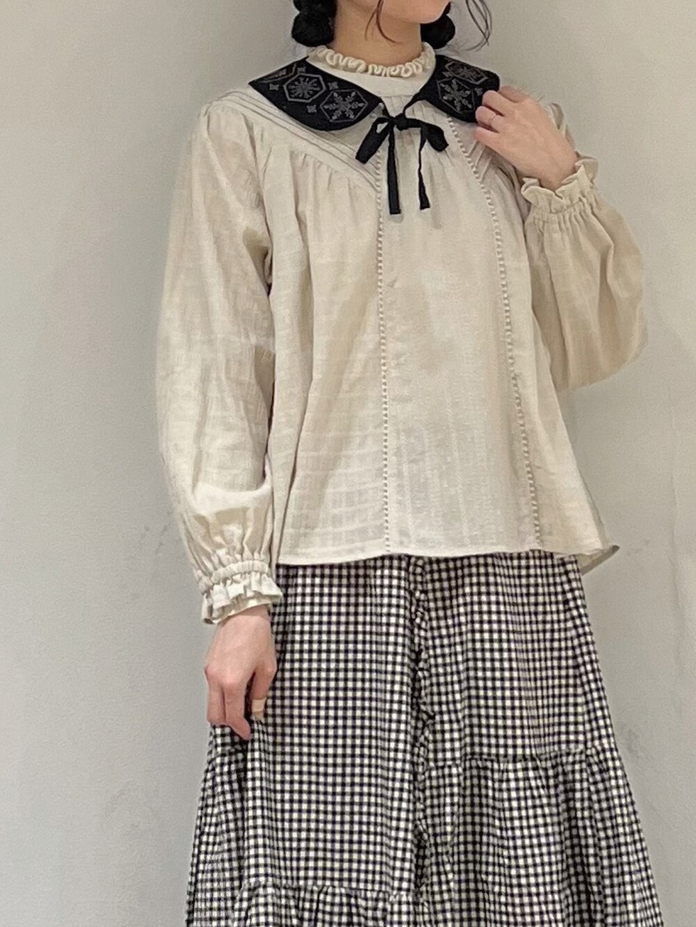 ベージュ系のシャツ/ブラウス、ブラック系のスカート、グレー系のカーディガン/ボレロを着用したレディースの冬コーディネートの5枚目の写真