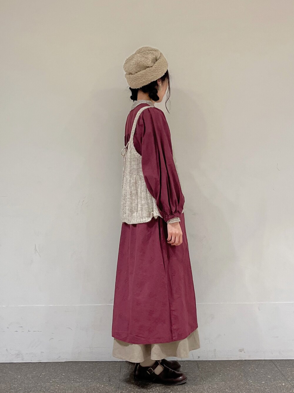 レッド系のワンピース、ホワイト系のニット/セーター、ベージュ系のスカートを着用したレディースの秋コーディネートの2枚目の写真