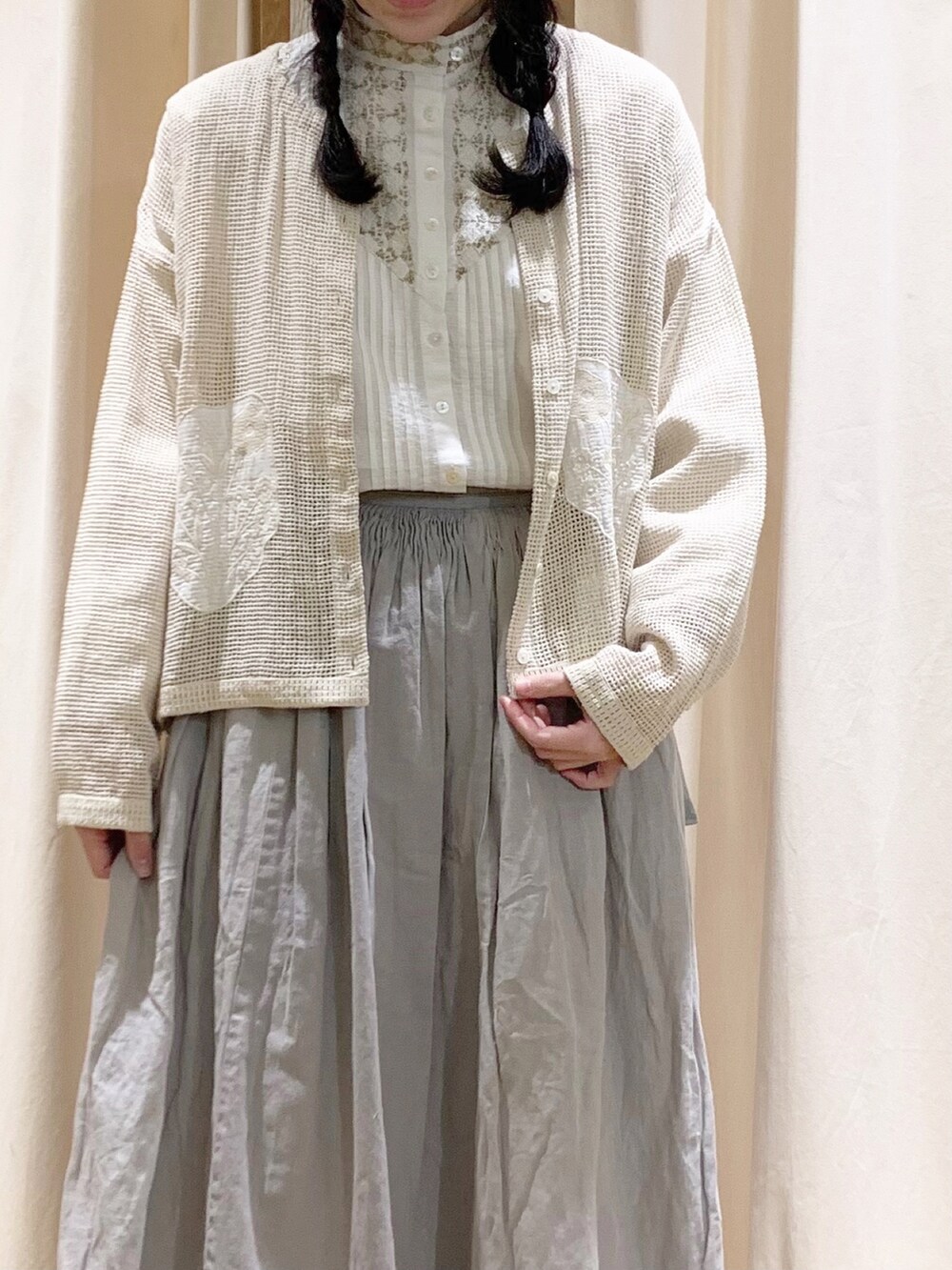 ホワイト系のシャツ/ブラウス、ホワイト系のカーディガン/ボレロ、グレー系のスカートを着用したレディースの春コーディネートの2枚目の写真