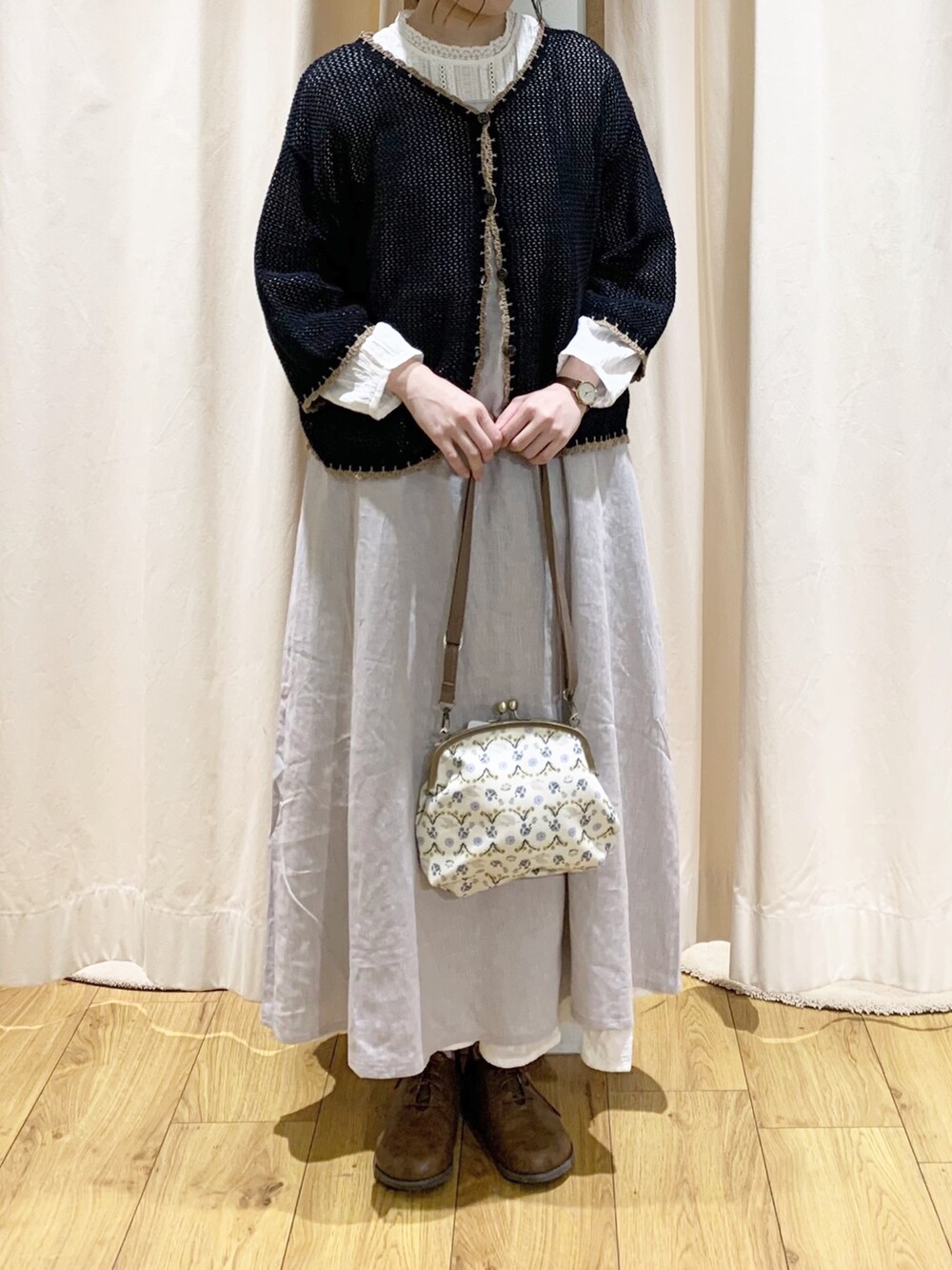 ブラック系のカーディガン/ボレロ、グレー系のワンピース、ベージュ系のハンドバッグを着用したレディースの春コーディネートの2枚目の写真