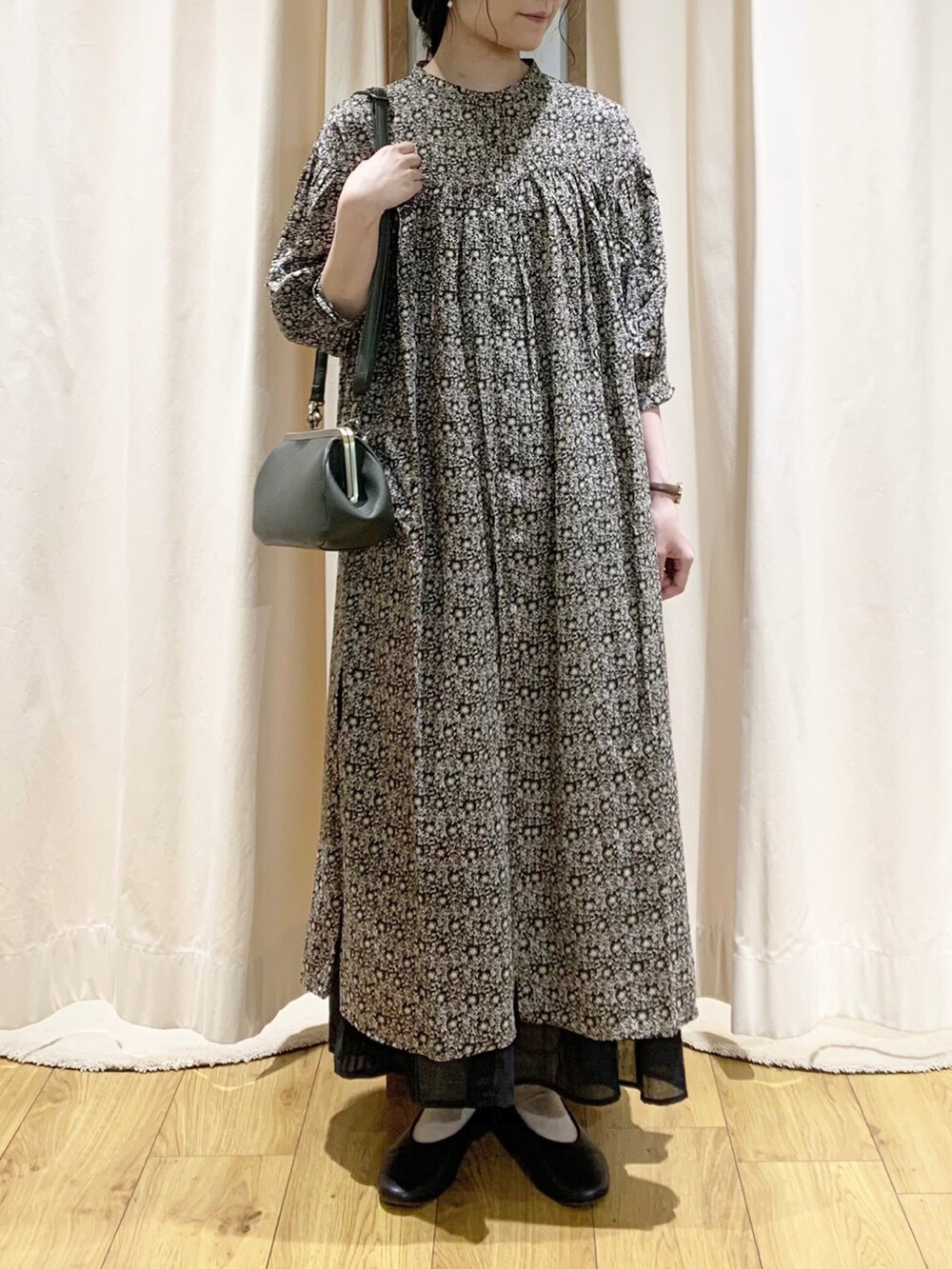 グレー系のワンピース、ホワイト系のTシャツ/カットソー、ブラック系のスカートを着用したレディースの夏コーディネートの2枚目の写真