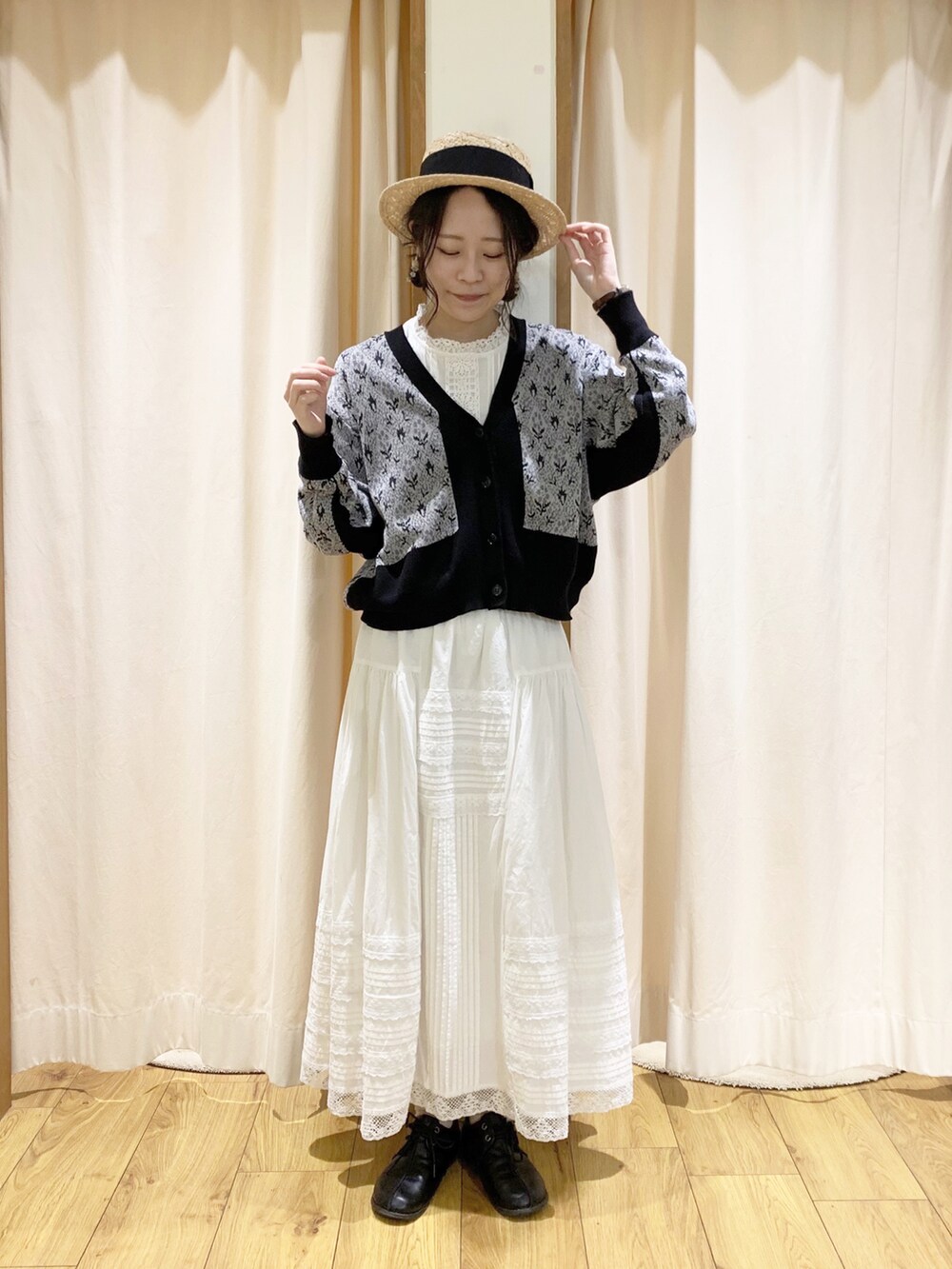 ブラック系のカーディガン/ボレロ、ホワイト系のスカート、ホワイト系のタンクトップを着用したレディースの春コーディネートの2枚目の写真