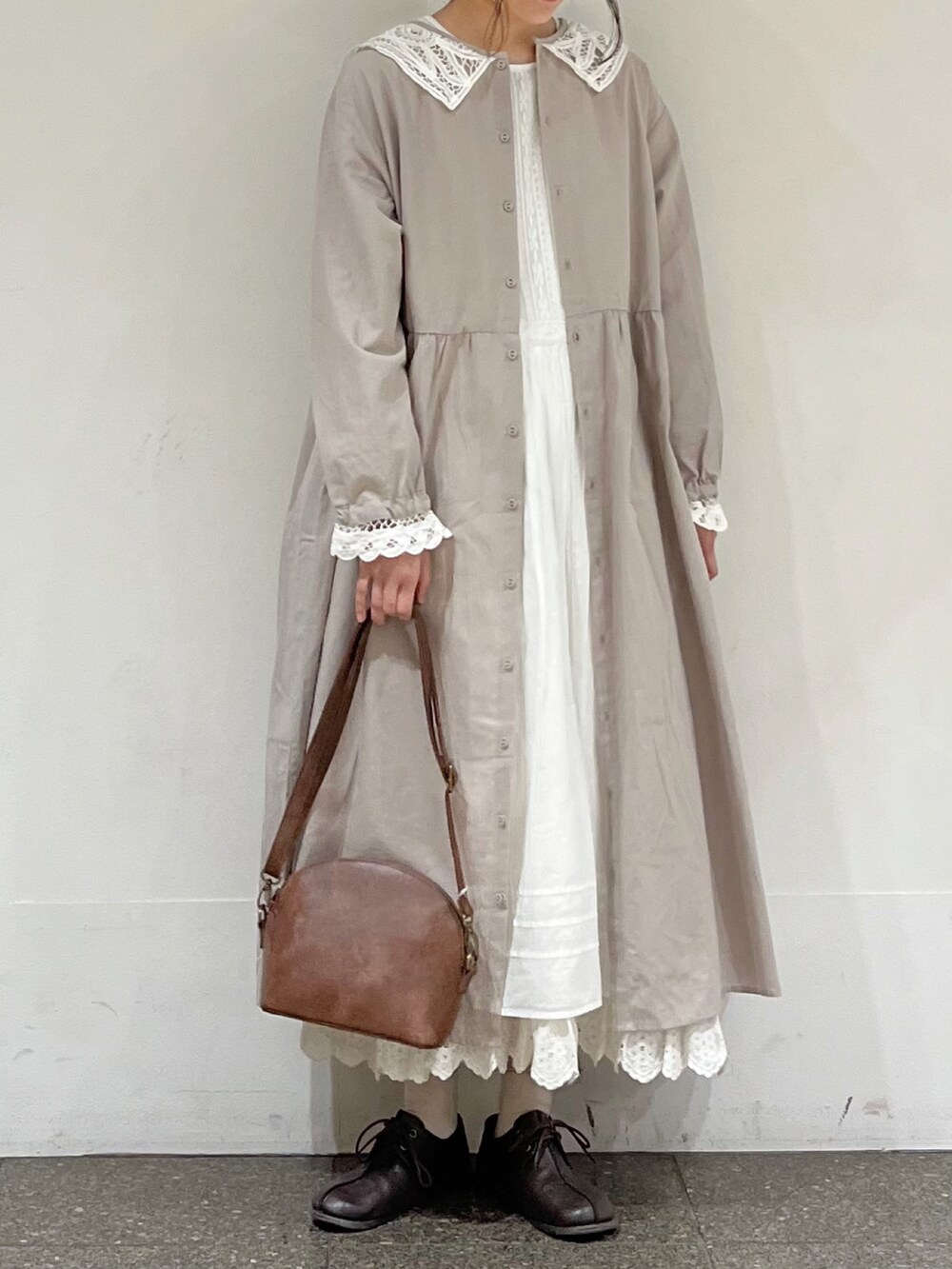 ホワイト系のワンピース、ホワイト系のスカート、ブラウン系のハンドバッグを着用したレディースの冬コーディネートの3枚目の写真