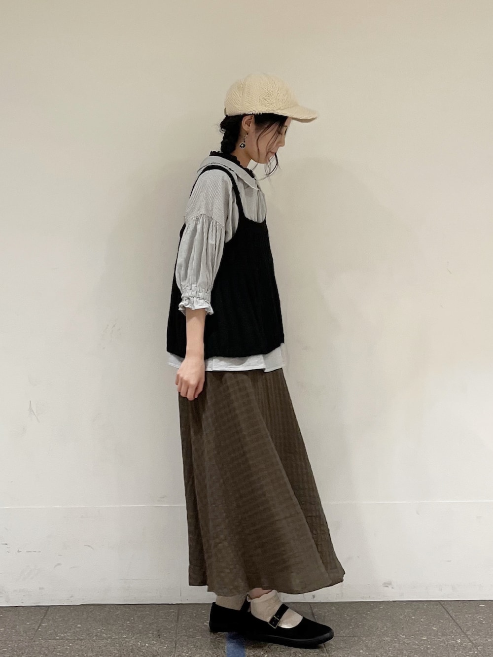 ブラック系のニット/セーター、グレー系のシャツ/ブラウス、ブラック系のタンクトップを着用したレディースの秋コーディネートの4枚目の写真