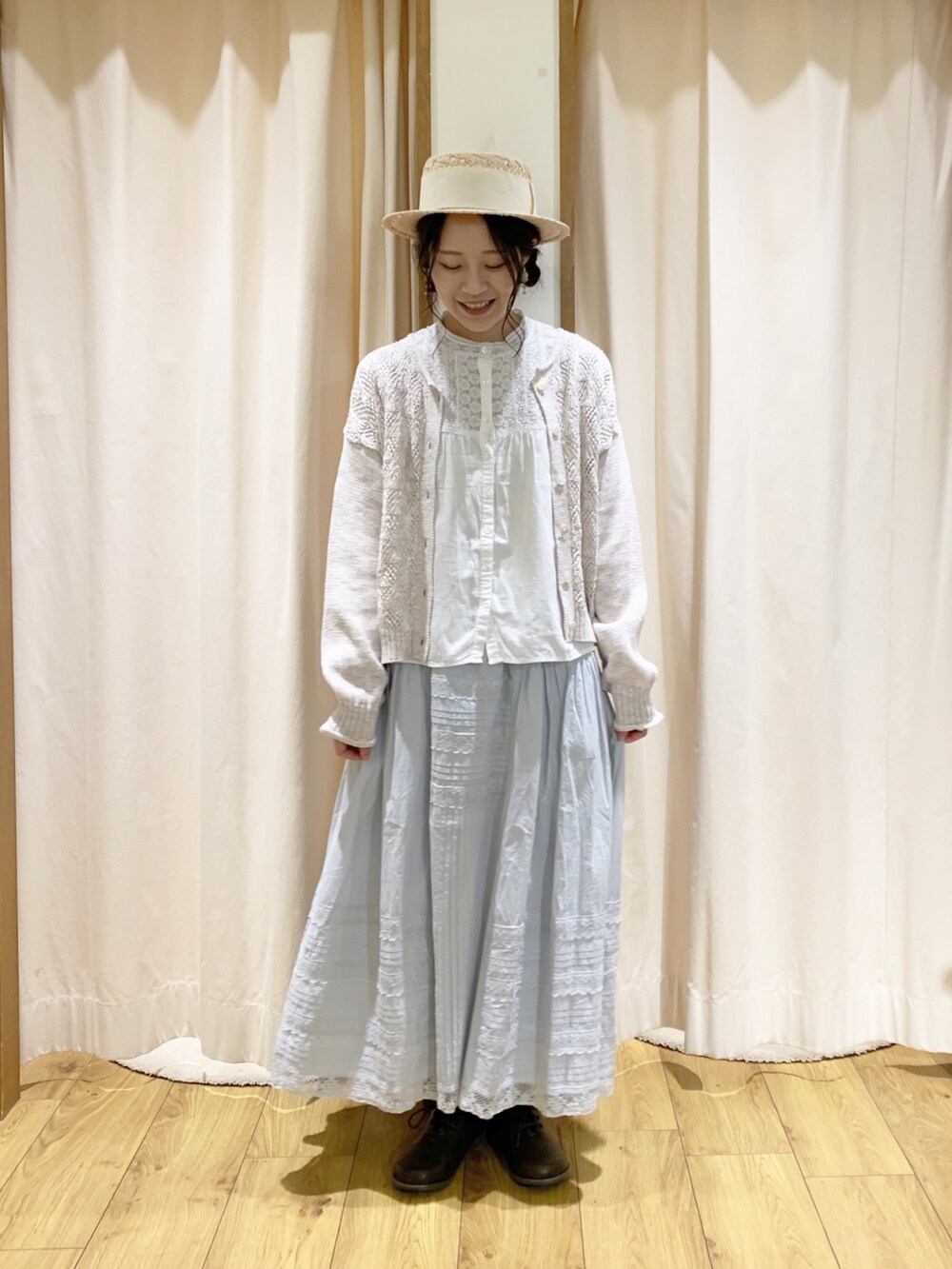 ホワイト系のカーディガン/ボレロ、ホワイト系のシャツ/ブラウス、ブルー系のスカートを着用したレディースの春コーディネートの2枚目の写真