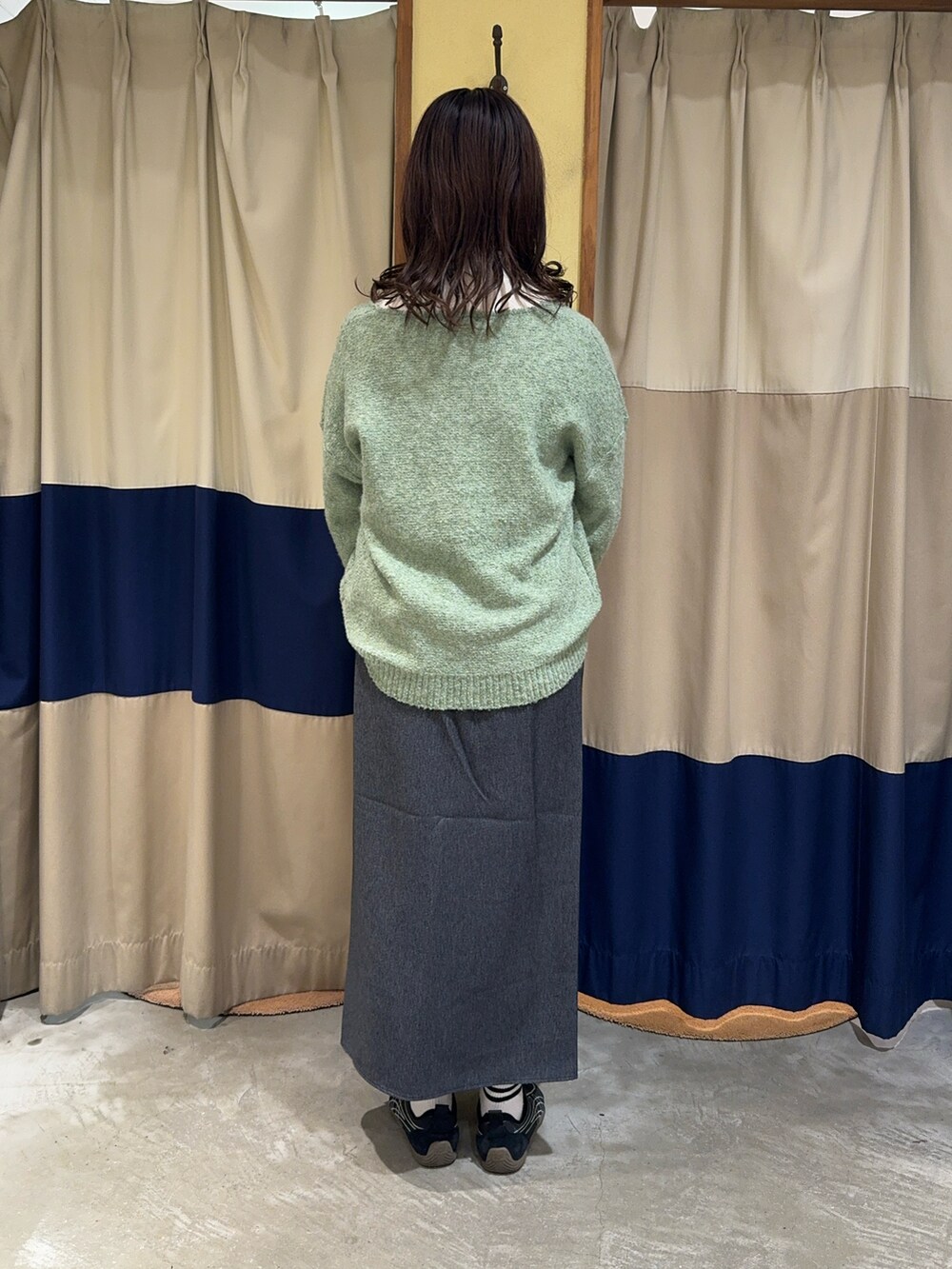 グリーン系のニット/セーター、ホワイト系のハンドバッグ、ブルー系のスカートを着用したレディースの冬コーディネートの2枚目の写真