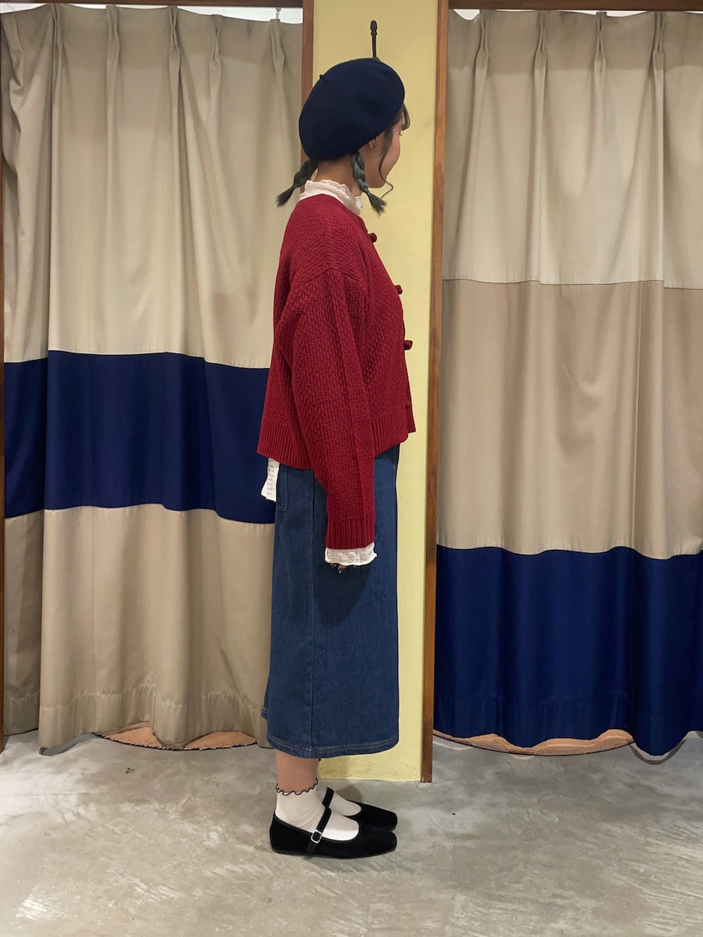 レッド系のカーディガン/ボレロ、ブルー系のスカート、ブラック系のドレスシューズを着用したレディースの秋コーディネートの2枚目の写真