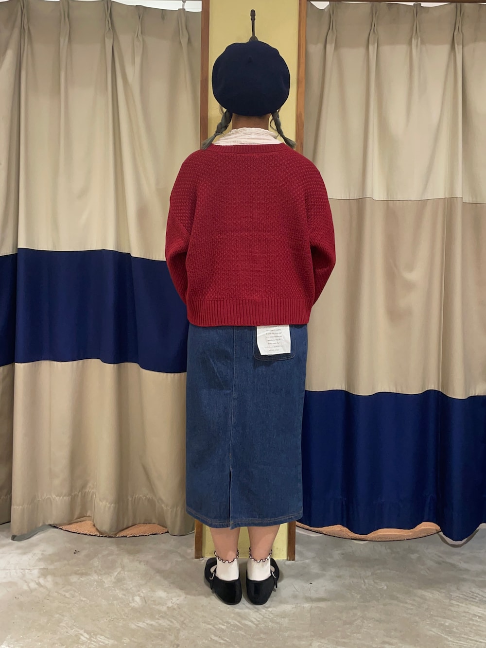 レッド系のカーディガン/ボレロ、ブルー系のスカート、ブラック系のドレスシューズを着用したレディースの秋コーディネートの3枚目の写真