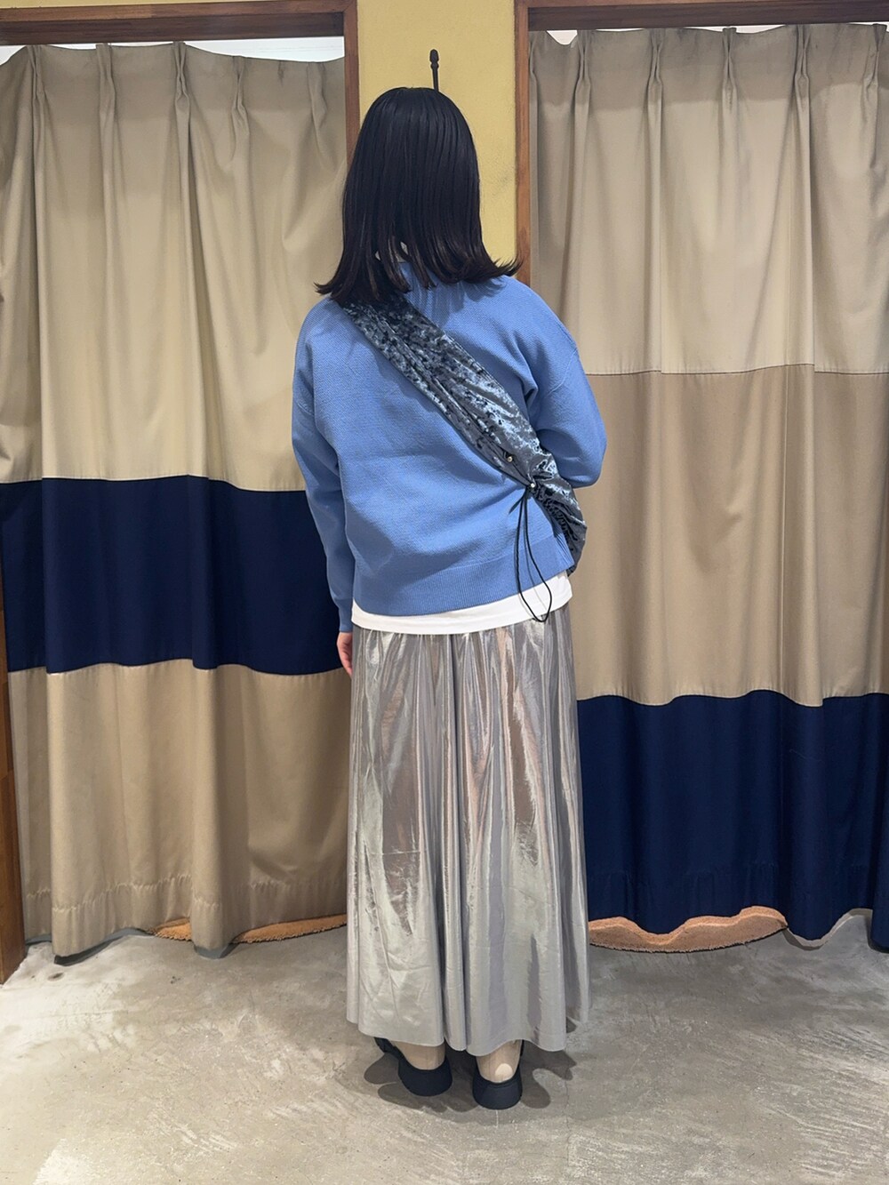 シルバー系のスカート、ブルー系のニット/セーターを着用したレディースの冬コーディネートの2枚目の写真