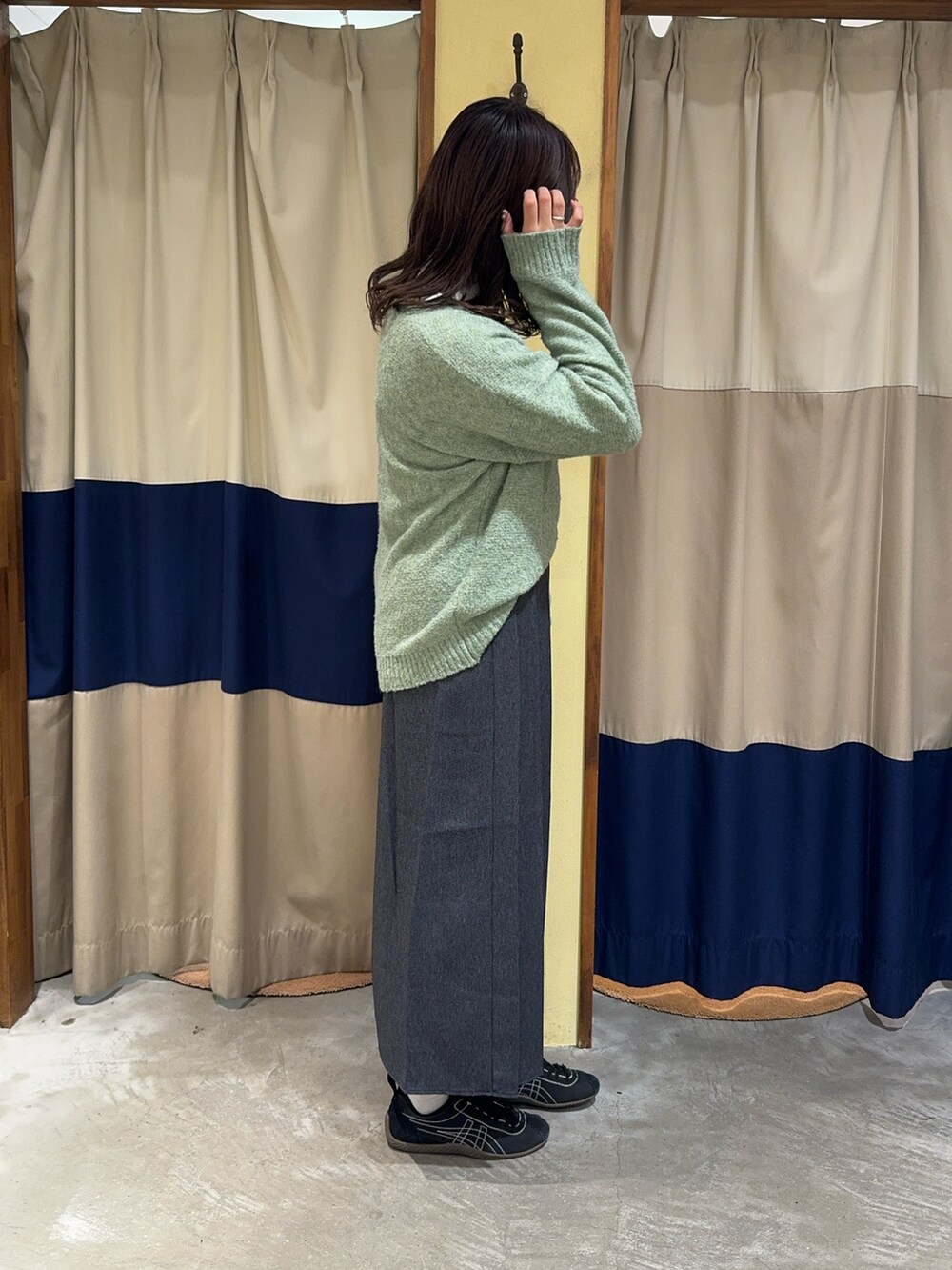 グリーン系のニット/セーター、ホワイト系のハンドバッグ、ブルー系のスカートを着用したレディースの冬コーディネートの3枚目の写真