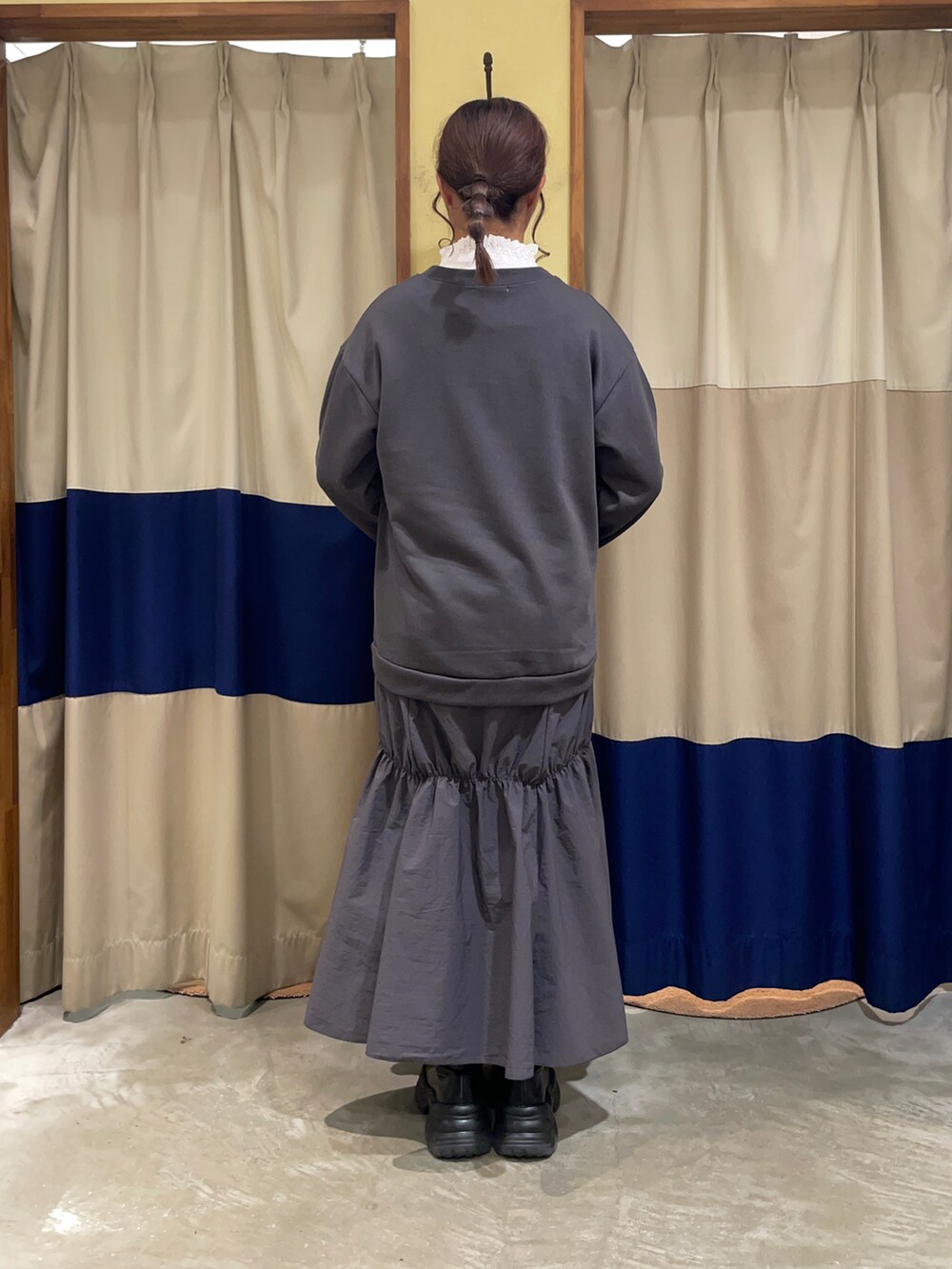 パープル系のハンドバッグ、グレー系のワンピースを着用したレディースの秋コーディネートの2枚目の写真