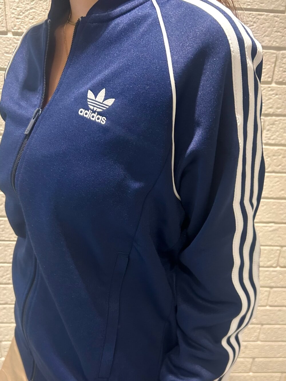 ホワイト系のシューズ、ブルー系のジャージ、ベージュ系のショルダーバッグを着用したレディースの秋コーディネートの2枚目の写真