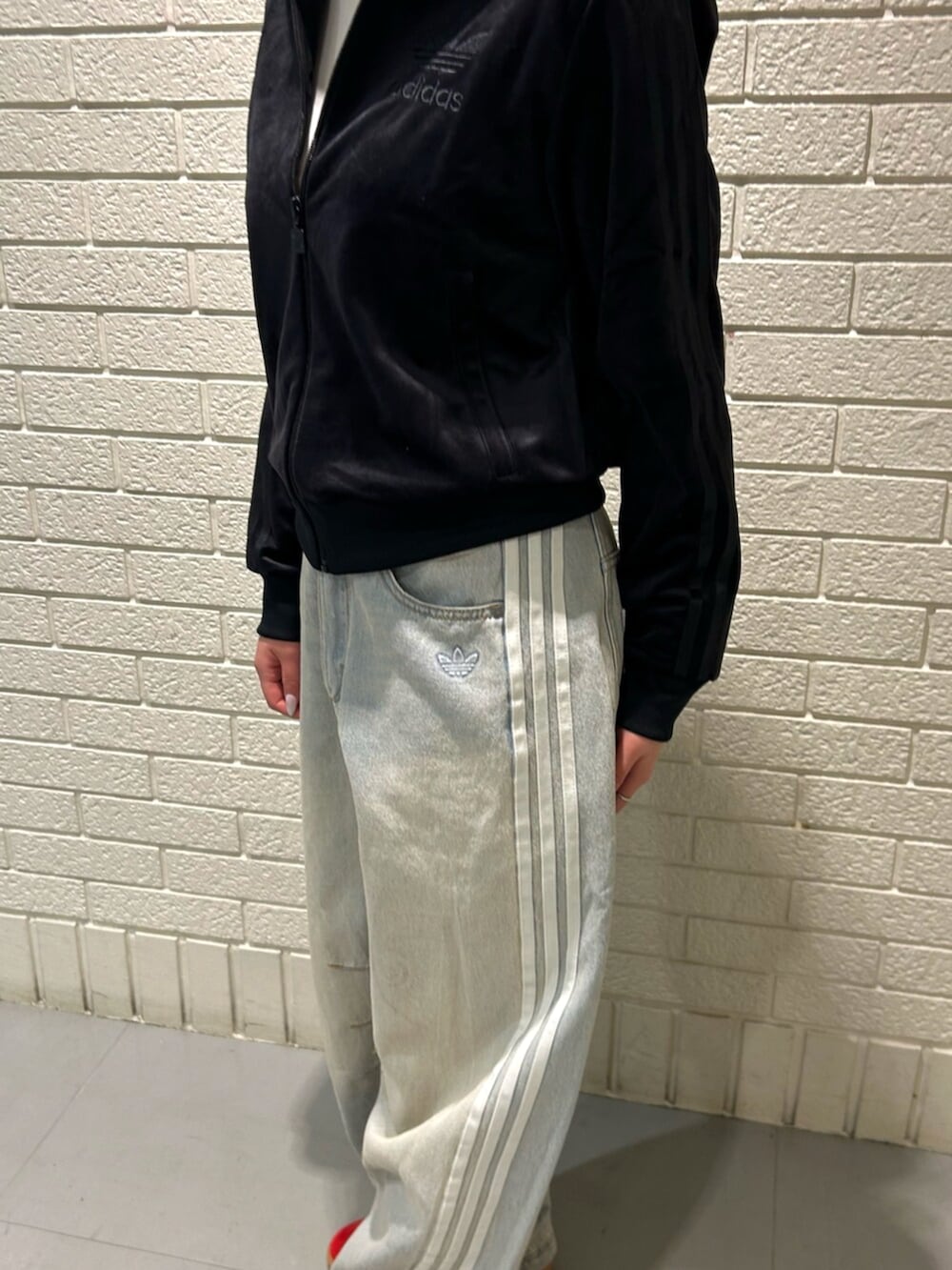 レッド系のスニーカー、ブラック系のジャージ、ブルー系のデニムパンツを着用したレディースの冬コーディネートの3枚目の写真