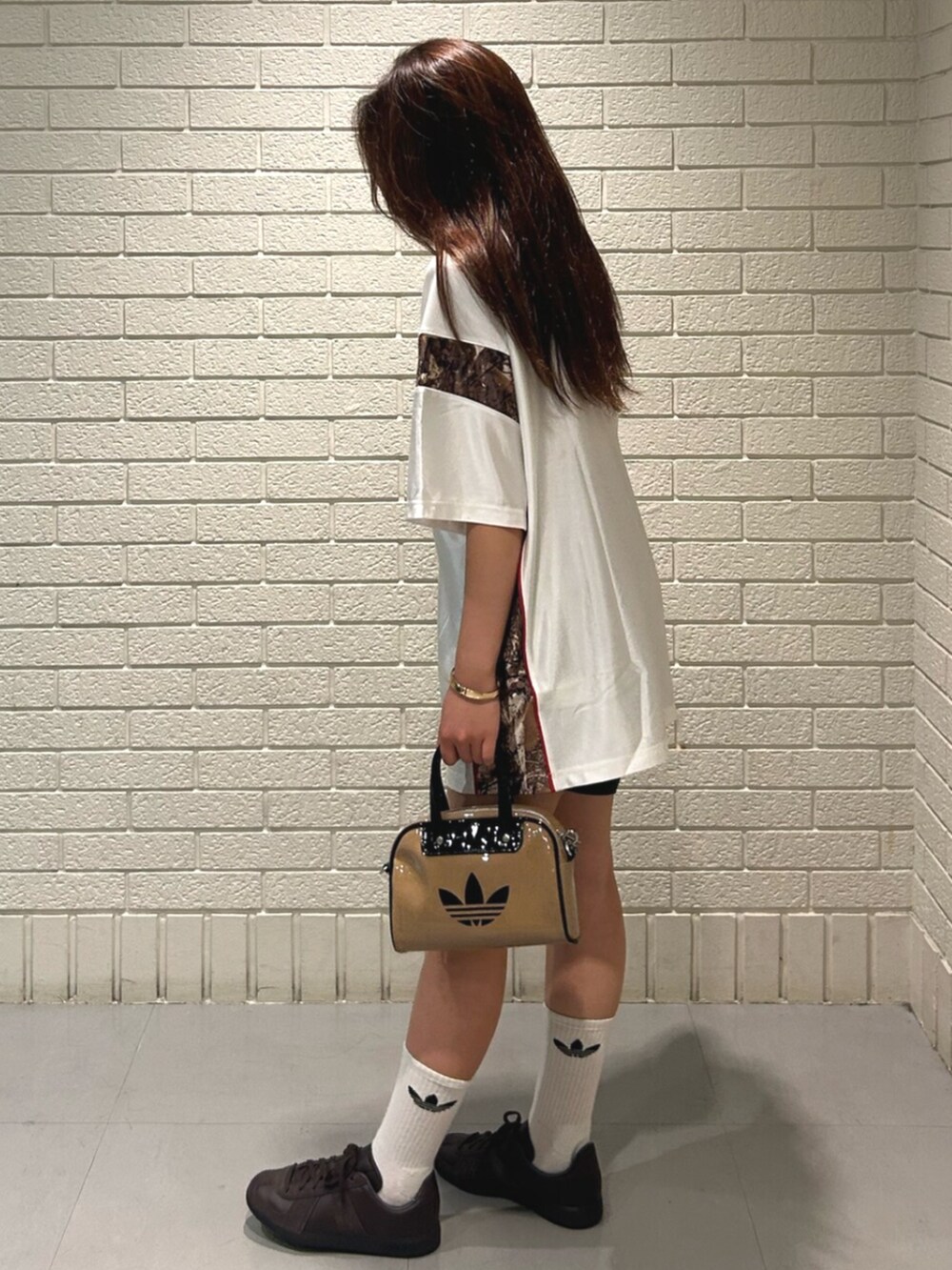 ホワイト系のトップス、ベージュ系のショルダーバッグ、ブラウン系のスニーカーを着用したレディースの夏コーディネートの2枚目の写真