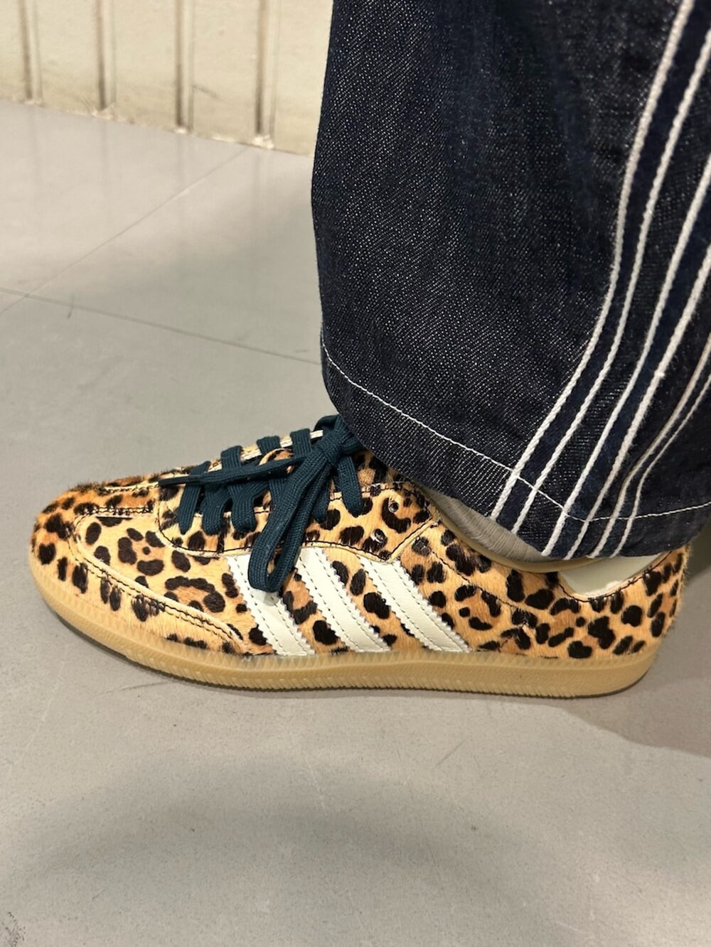 ベージュ系のスニーカー、ブラック系のジャージ、ブルー系のデニムパンツを着用したレディースの冬コーディネートの4枚目の写真