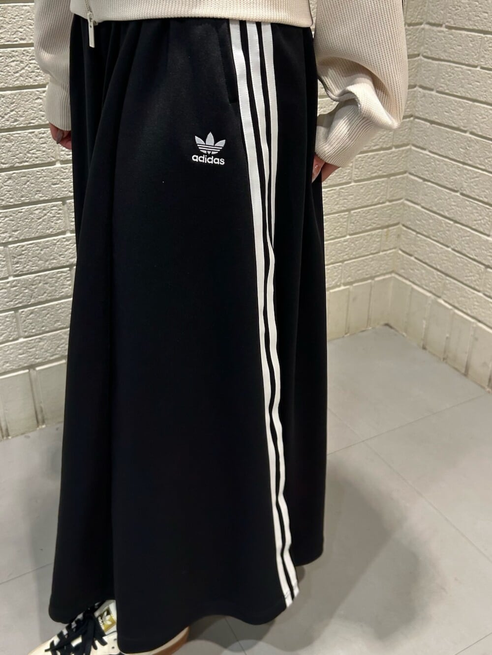 ホワイト系のスニーカー、ホワイト系のジャージ、ブラック系のスカートを着用したレディースの冬コーディネートの3枚目の写真