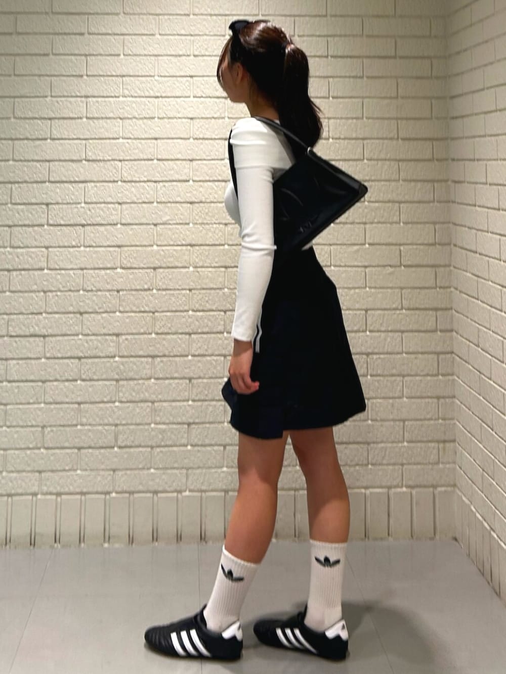 ホワイト系のTシャツ/カットソー、ブラック系のシューズ、ブラック系のショルダーバッグを着用したレディースの夏コーディネートの2枚目の写真