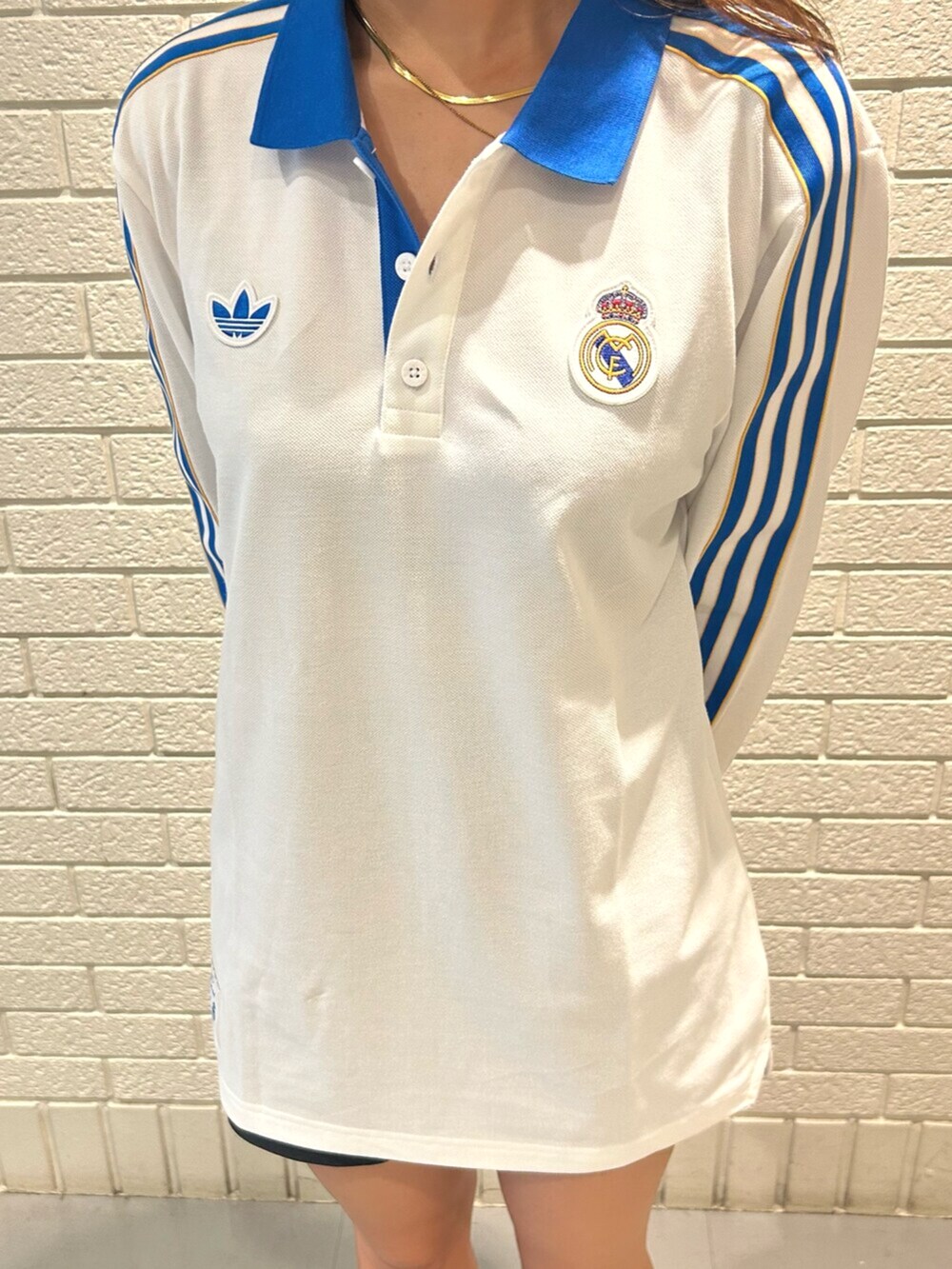 ホワイト系のポロシャツ、ブルー系のスニーカーを着用したレディースの夏コーディネートの3枚目の写真